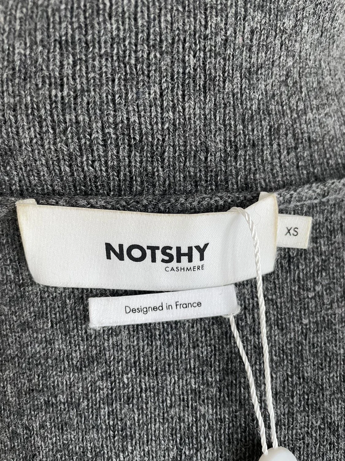 Close-up of the interior "NOTSHY Cashmere" brand label and "Designed in France" tag.