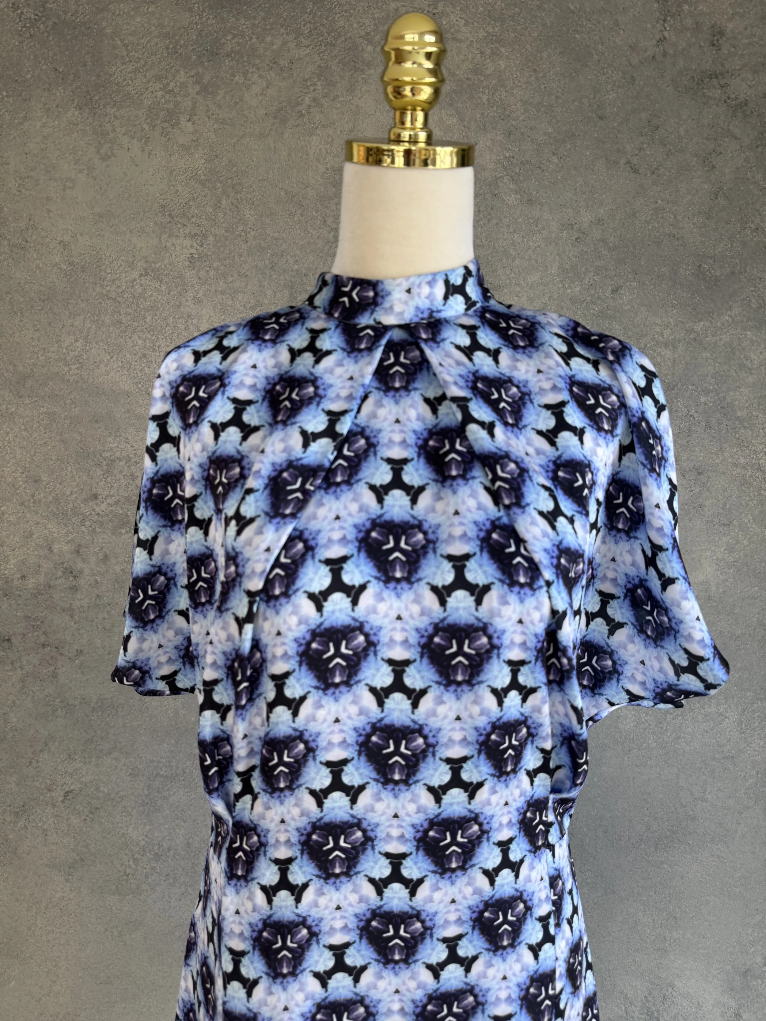 Close-up of the mini-dress hem, showing the transition between the kaleidoscope print and the geometric border.