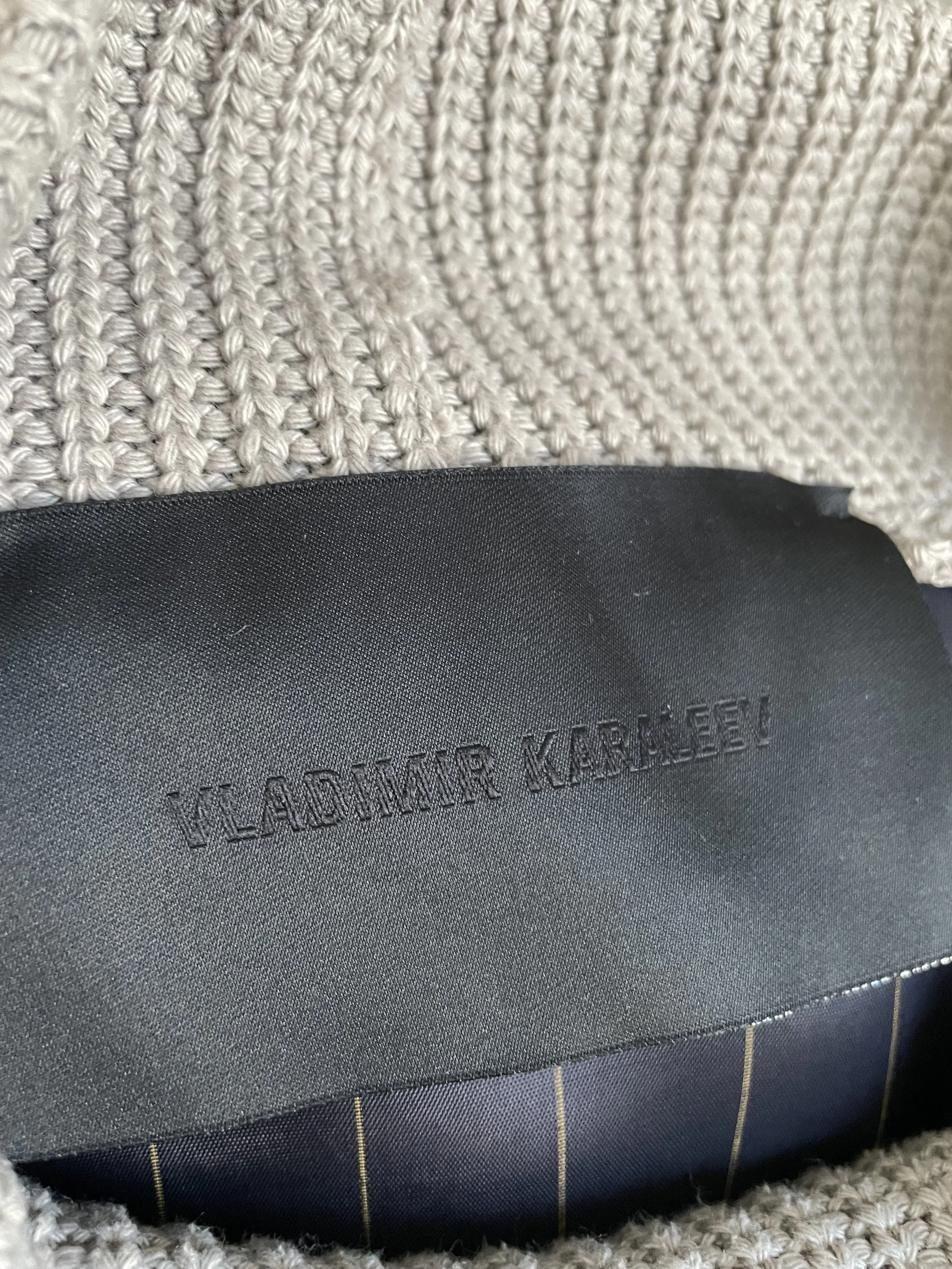 Close-up of the black internal brand tag reading "VLADIMIR KARALEEV" on the garment interior.