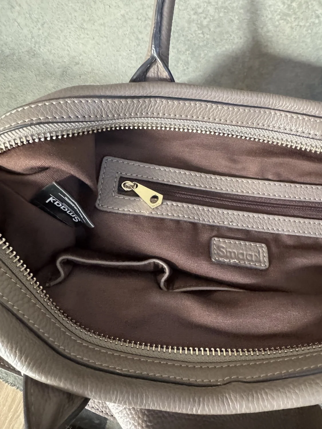 Interior view of Smaak Amsterdam bag with brown fabric lining and leather brand patch"