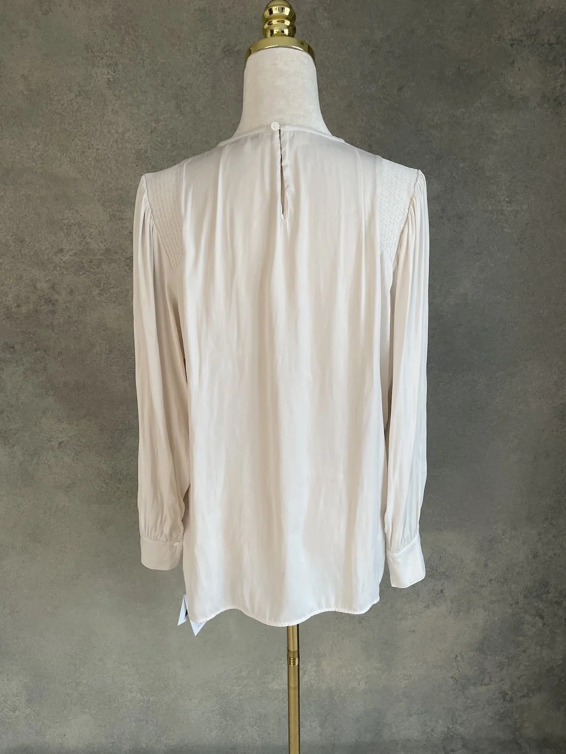 Back view of the Gigue beige blouse showing the keyhole button closure at the upper neckline and relaxed fit.