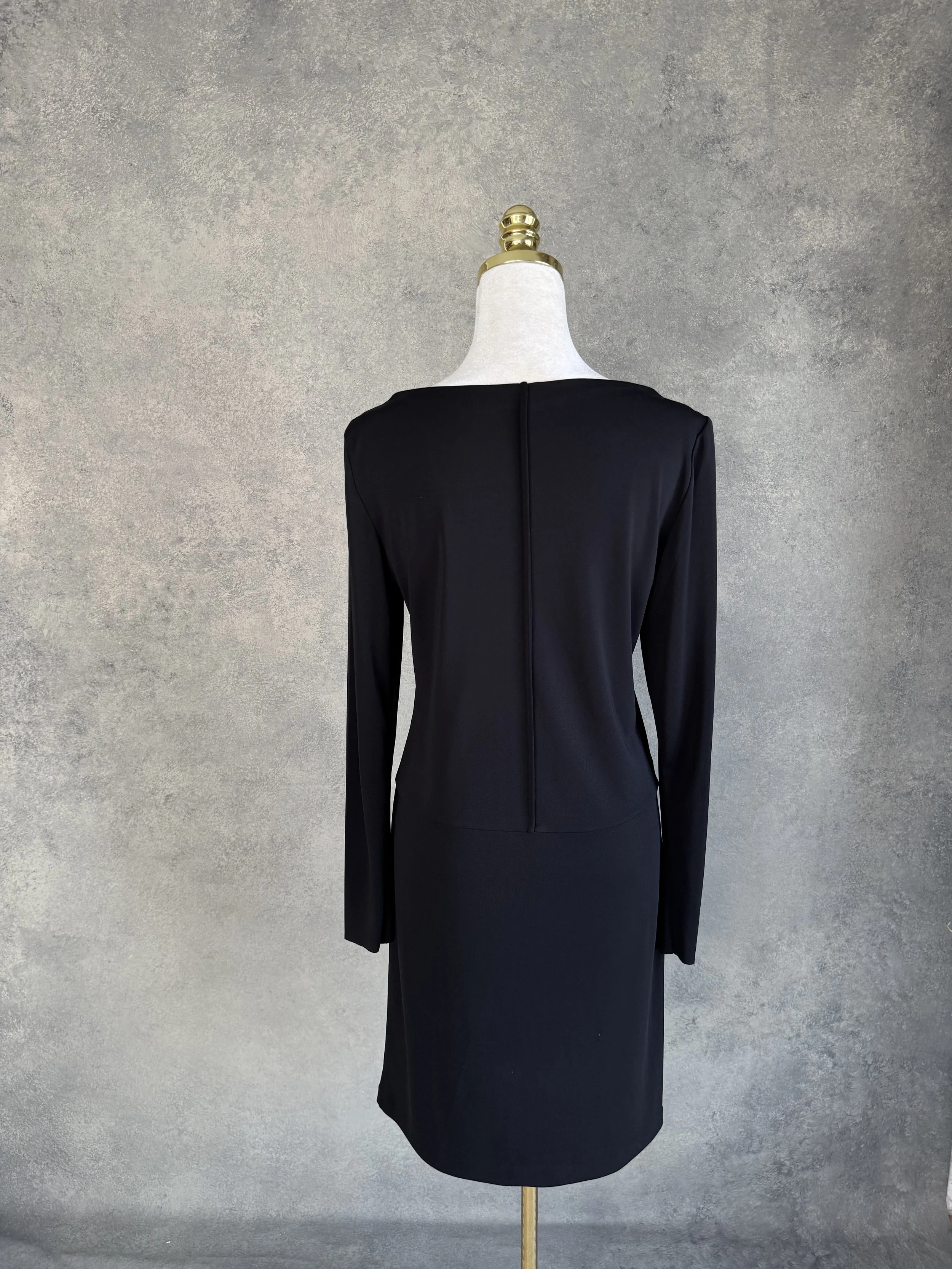 Back view of the black Filippa K dress on a mannequin, displaying the matching vertical center seam running down the back.