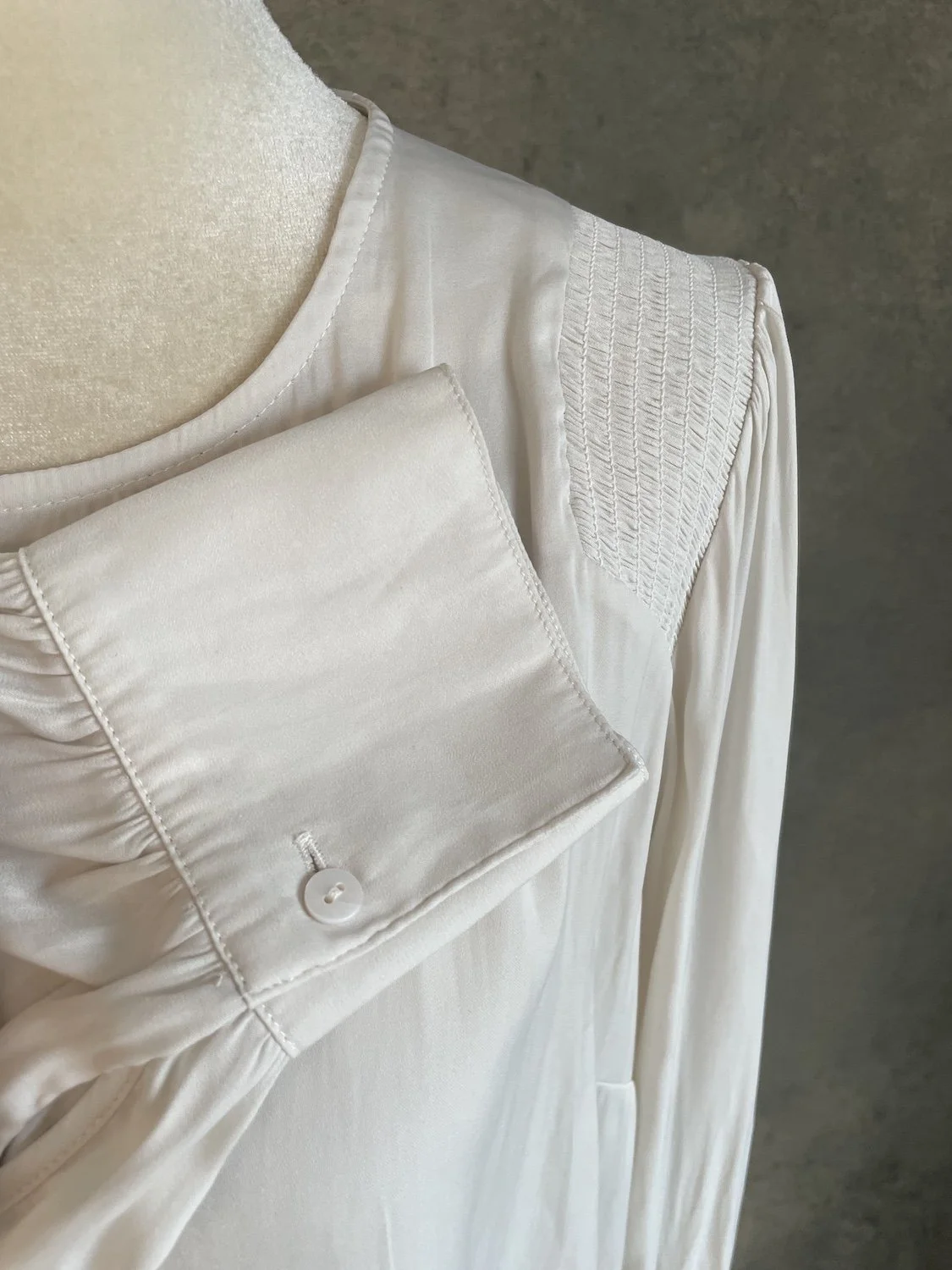Close-up of the structured button cuff and pleating on the sleeve of the Gigue beige blouse.