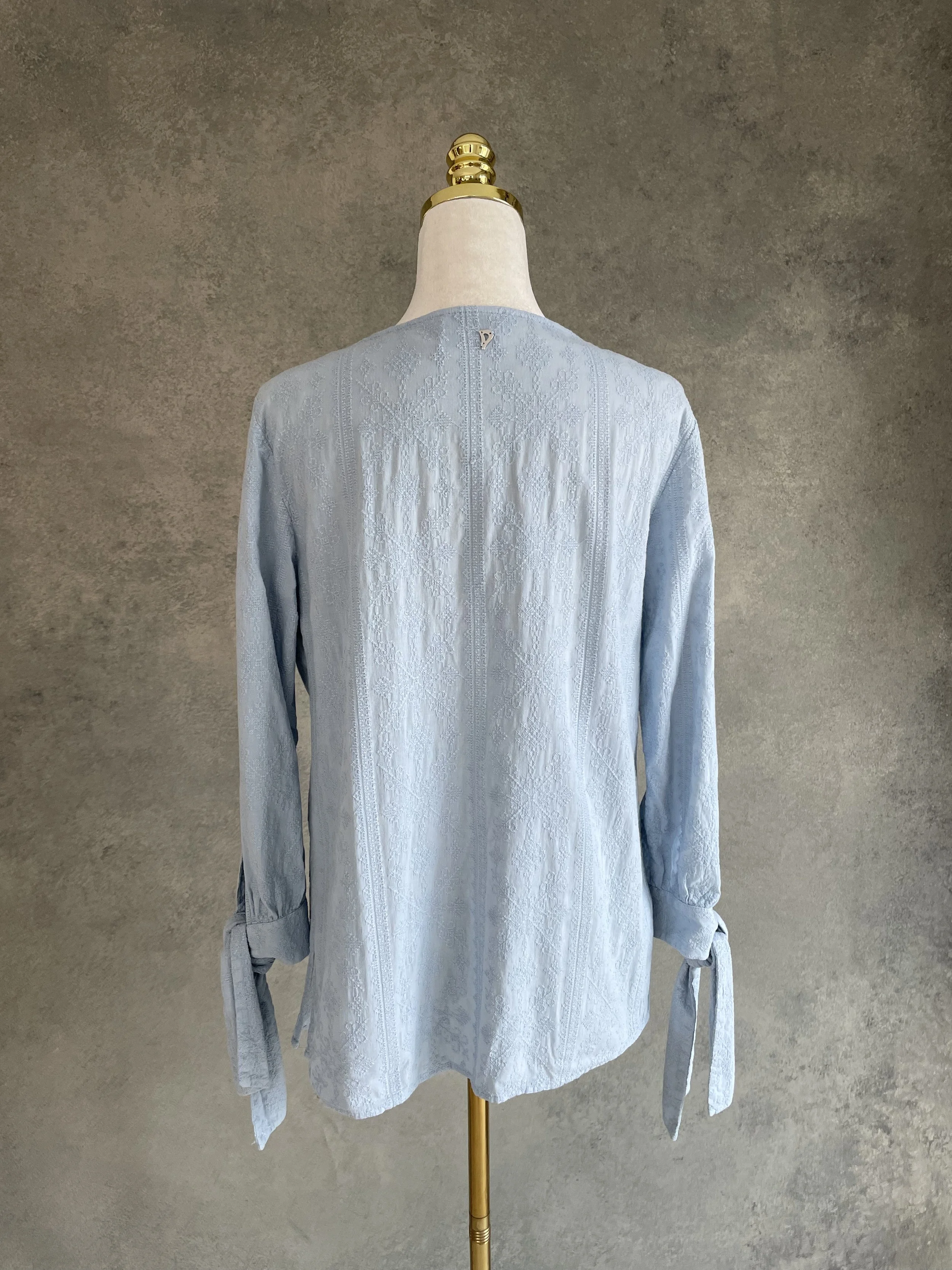 Back view of the light blue Dondup blouse on a mannequin, showing the silver 'D' logo on the neck.