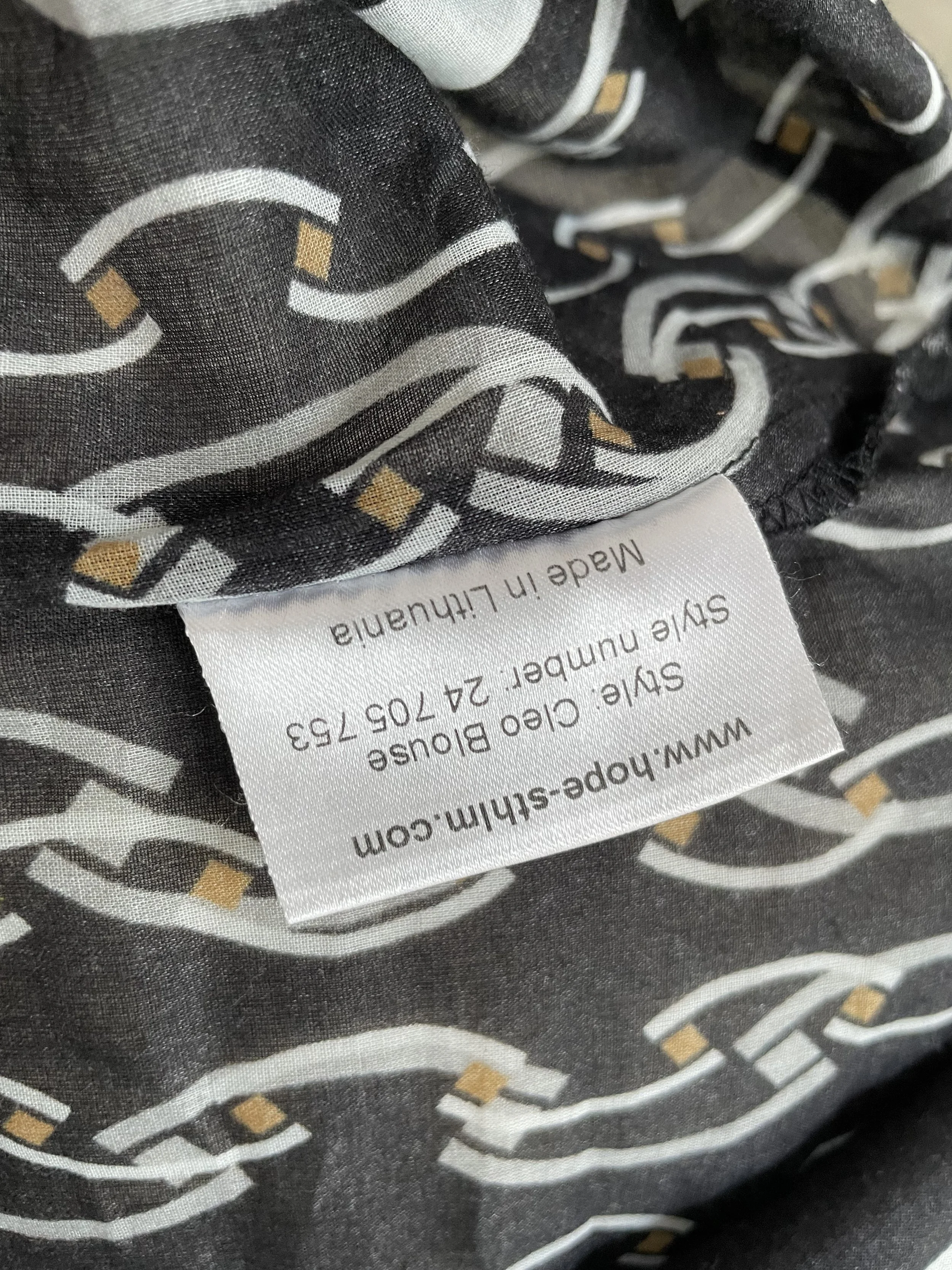 Detailed fabric care tag showing "Style: Cleo Blouse" and "Made in Lithuania".