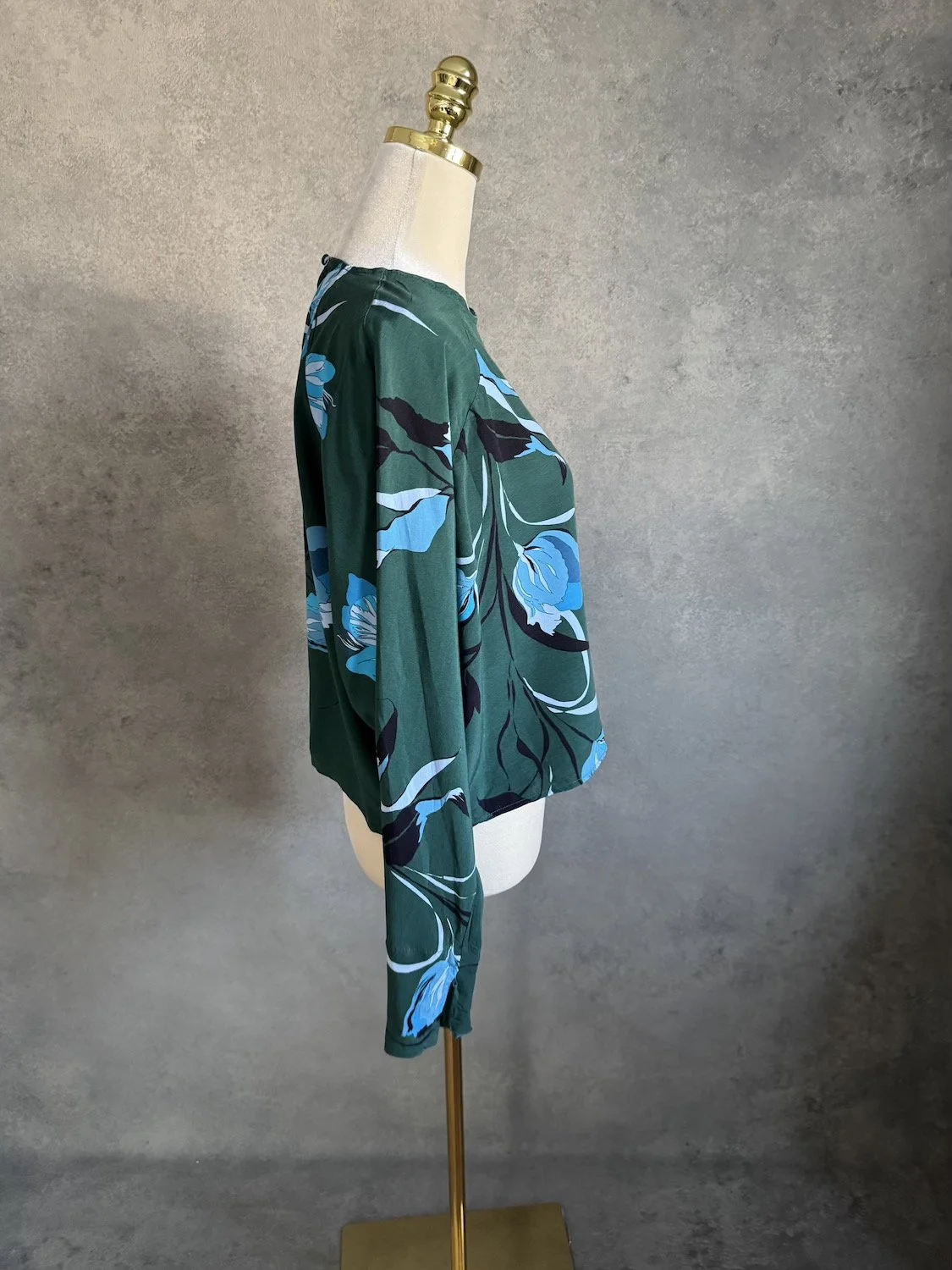 Side profile view of Gestuz green floral cropped blouse on mannequin