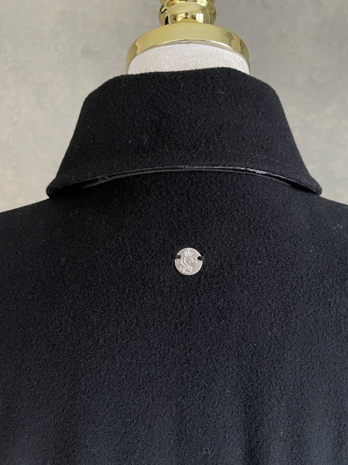 Scapa black coat back collar detail with metal logo stud