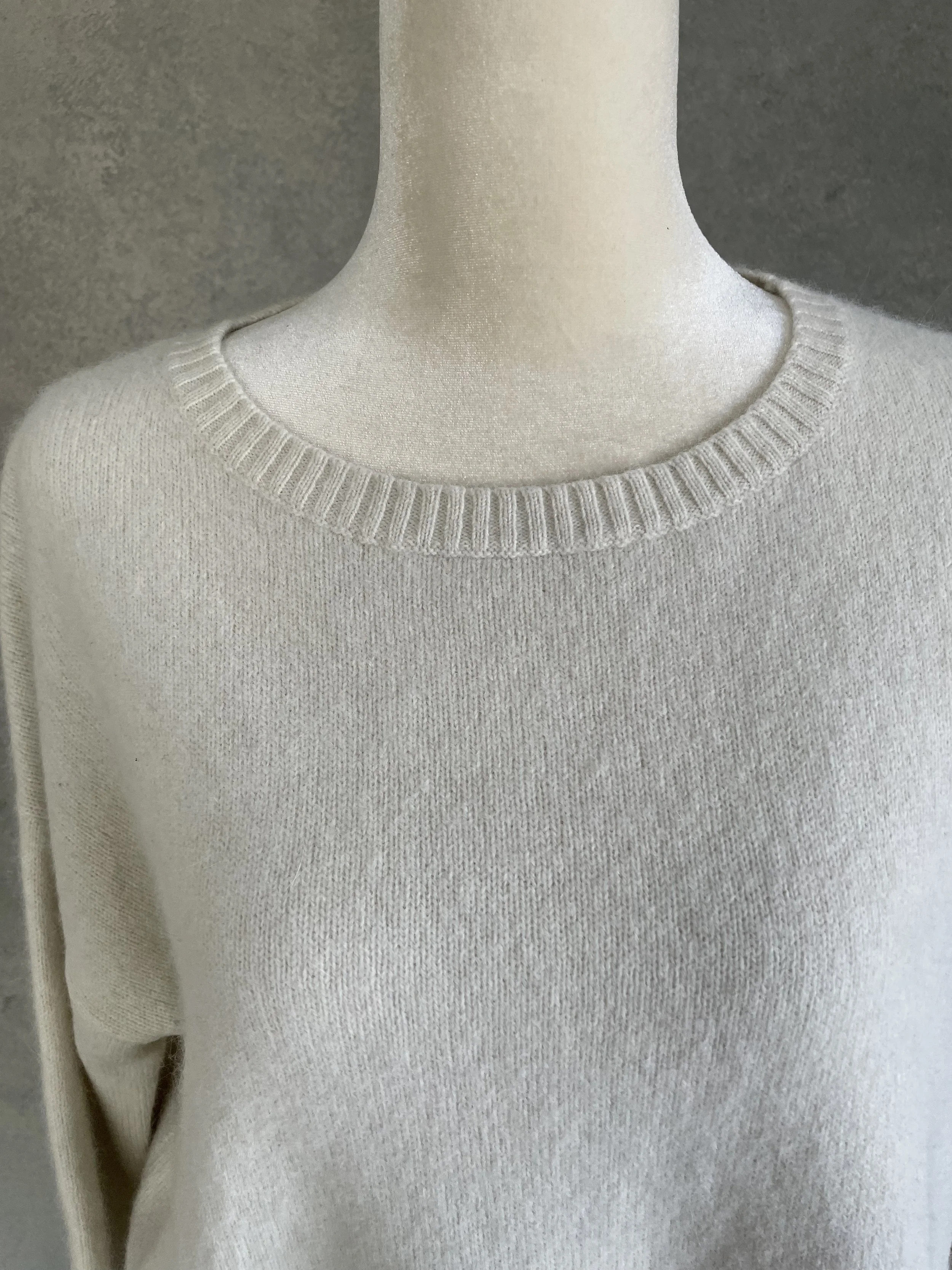 Close-up of the round neckline on a cream Rue Blanche knit sweater.