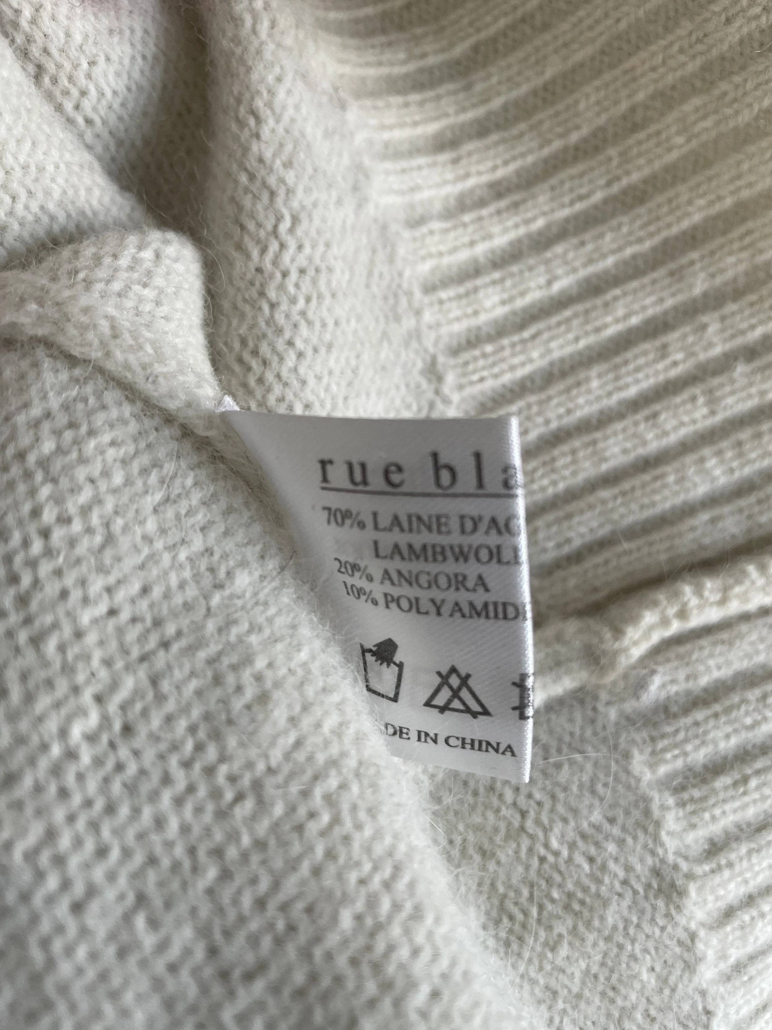 Detail shot of the Rue Blanche care and material label showing 70% lambswool, 20% angora, and 10% polyamide