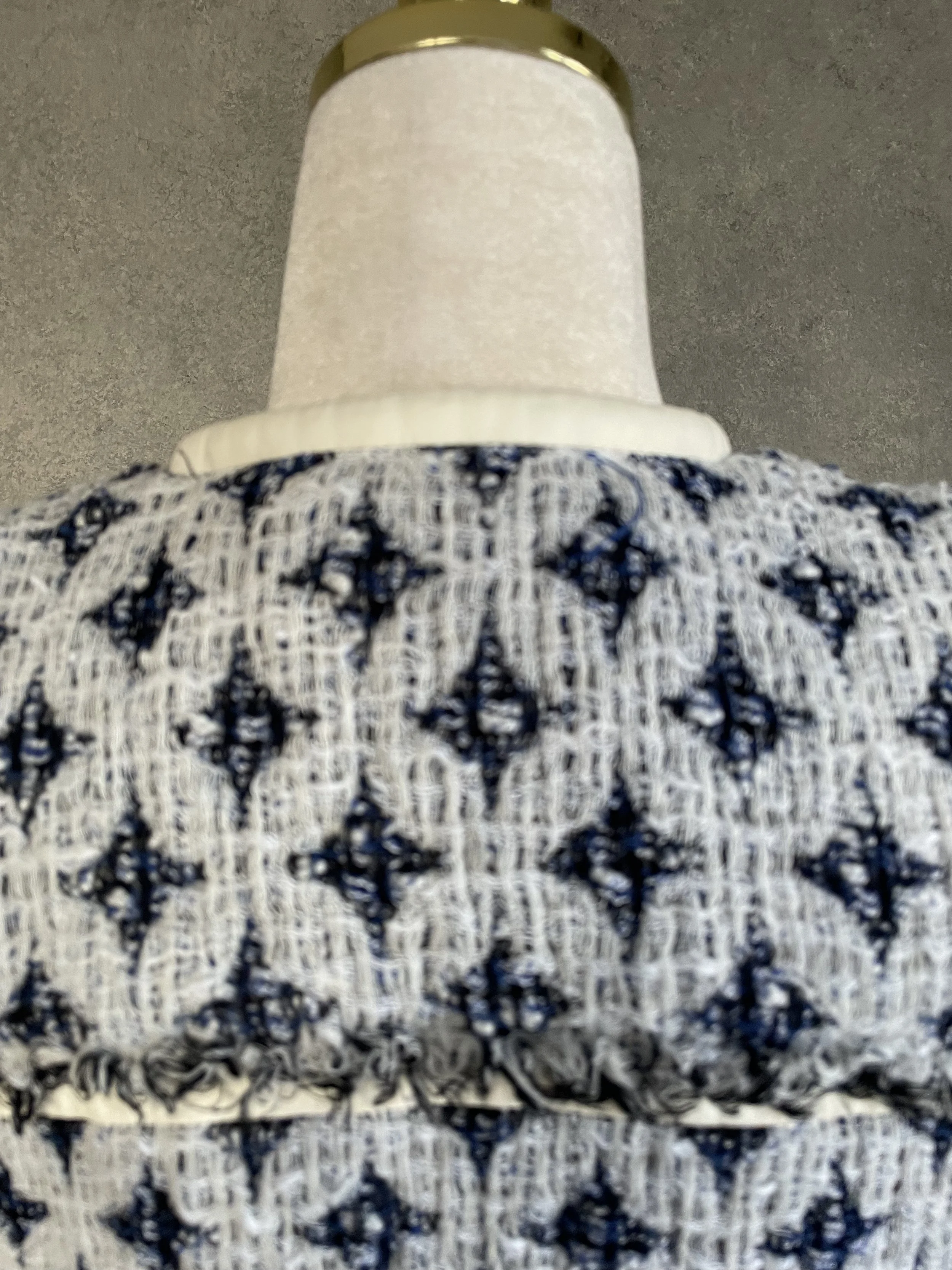 Close-up detail of the woven blue-and-white diamond texture and horizontal leather trim on the back of the IRO jacket.