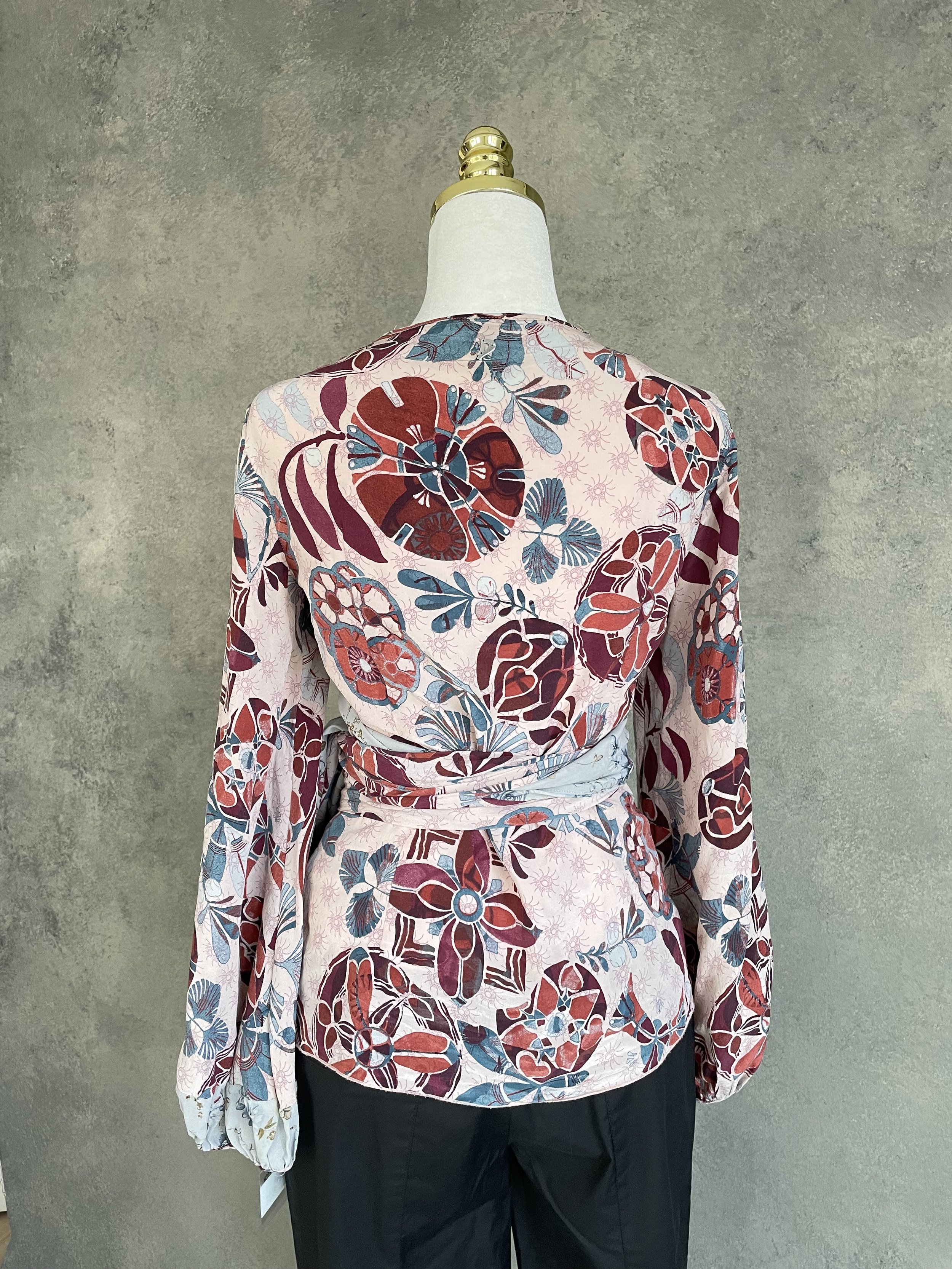 Full back view of the Dondup graphic print silk wrap blouse, styled with black trousers on a mannequin.