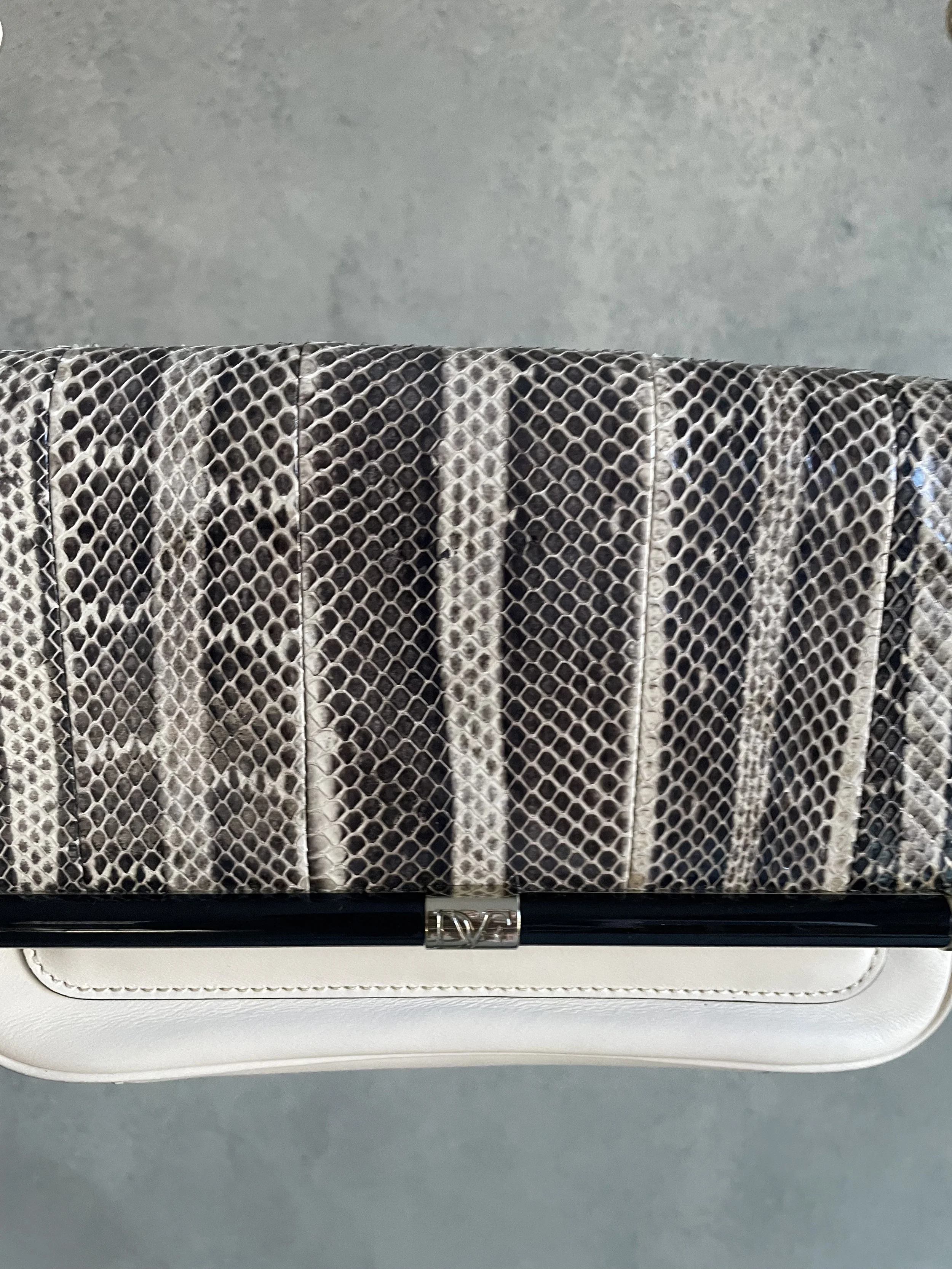 Close-up of the iconic DVF 440 metal bar closure on the snakeskin-print flap, highlighting the pristine condition of the hardware.
