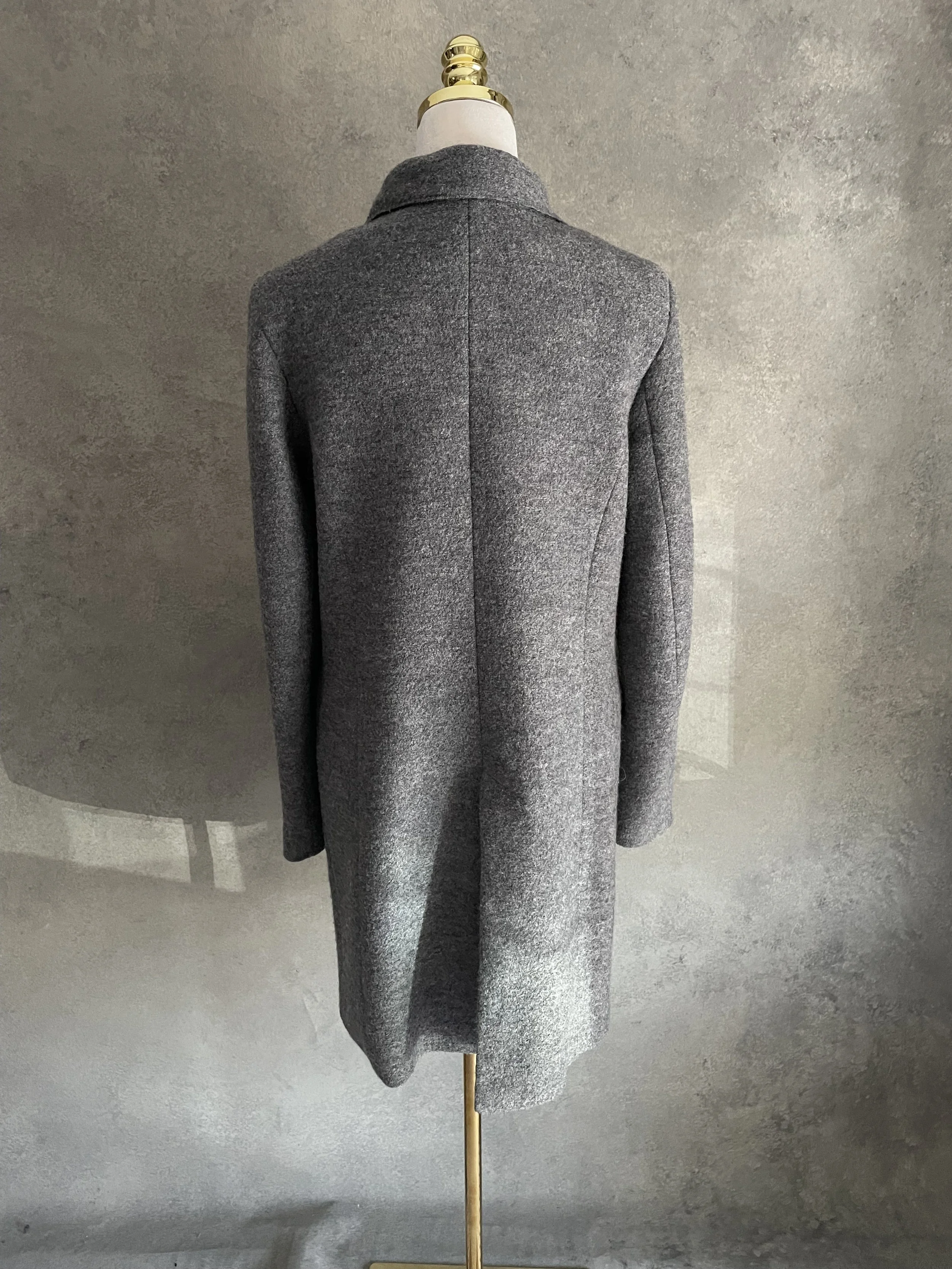 Back view of the Closed grey wool coat on a mannequin, highlighting the clean lines and tailored silhouette.