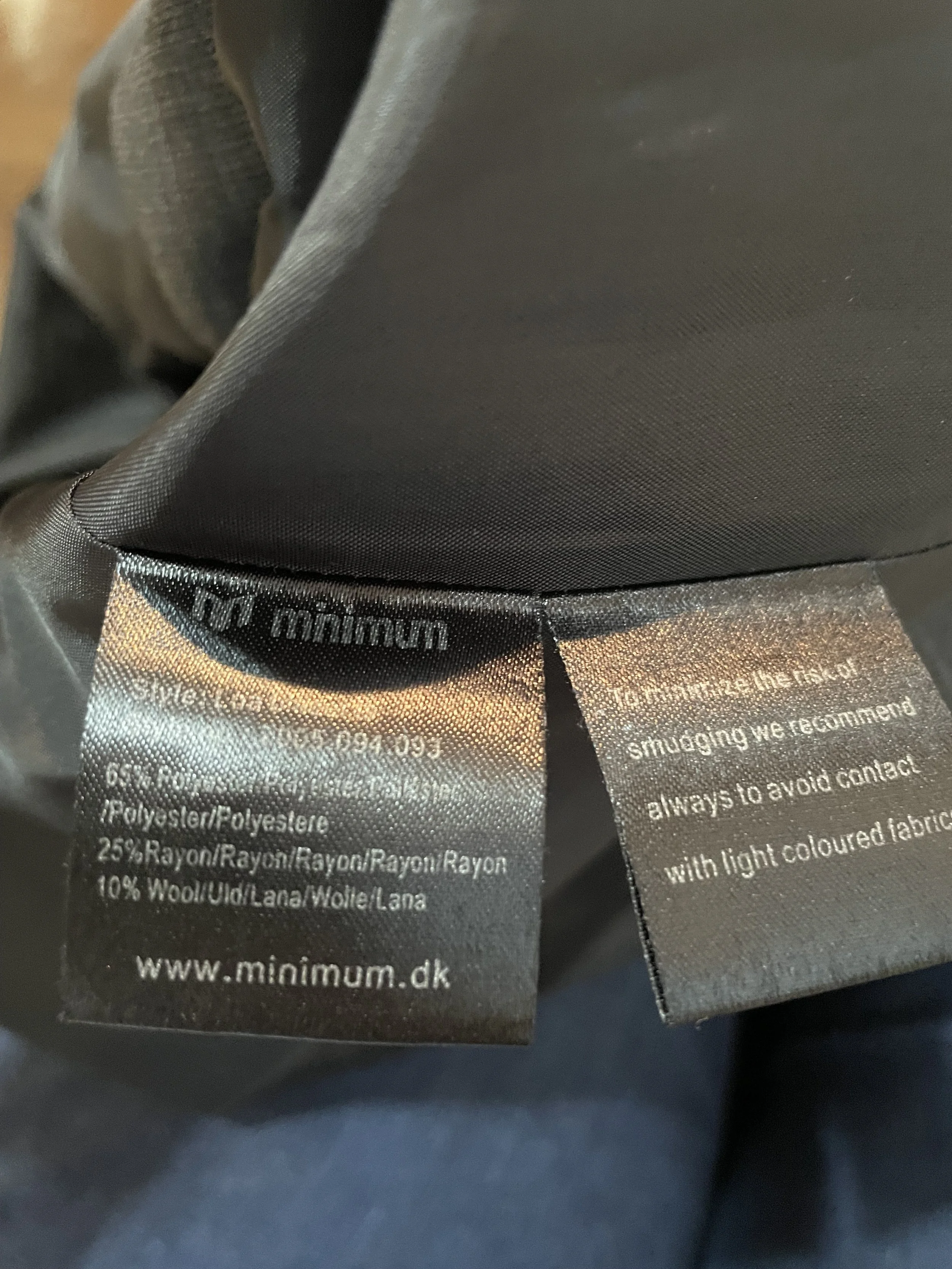 Close-up of the interior care and composition labels detailing the polyester-rayon-wool blend, style name 'Lea', and care recommendations.