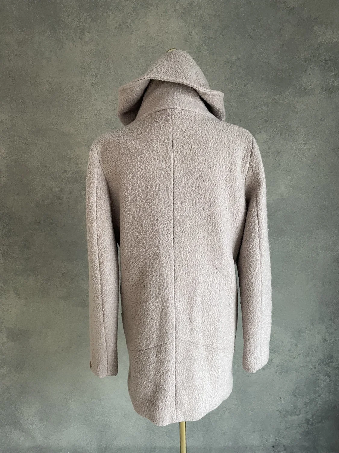 Full back view of the beige textured coat with center seam detail.
