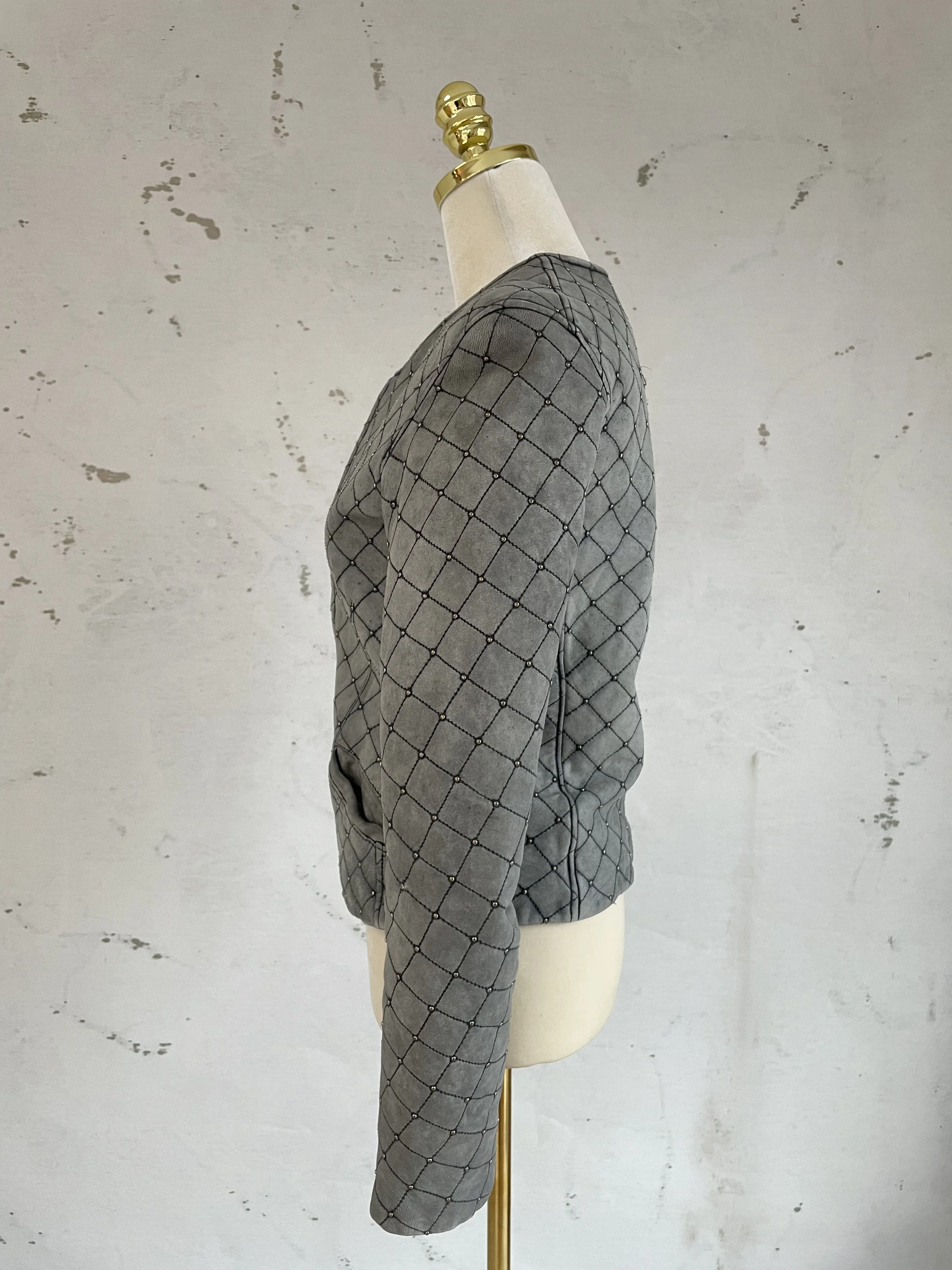 Side profile of Iro grey leather jacket featuring diamond-quilted pattern and metallic stud accents.