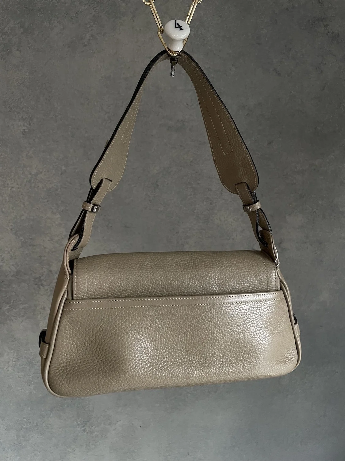 Close-up macro detail of the beige pebbled leather front flap and embossed branding