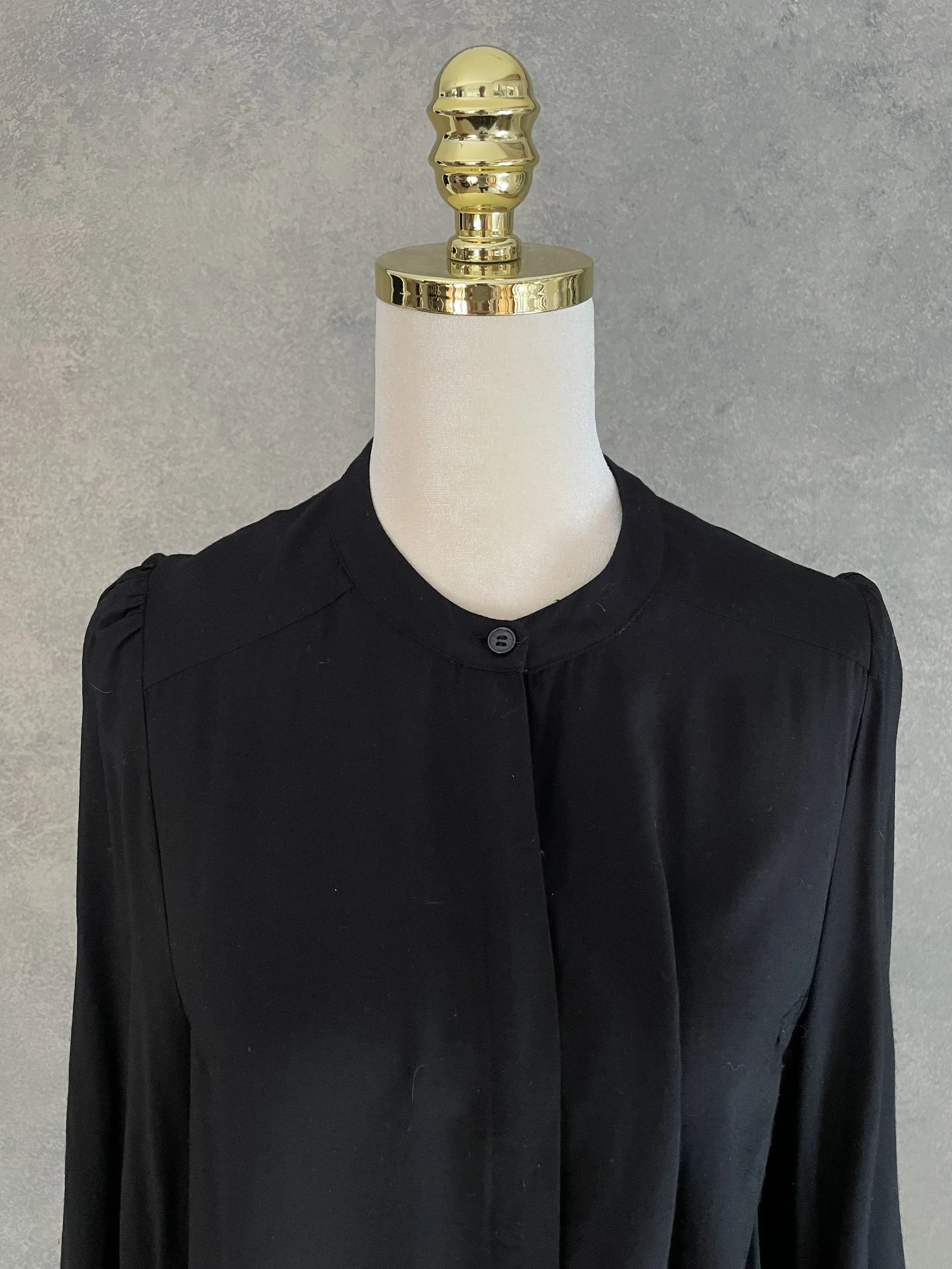 Detailed close-up of the clean round neck and concealed button placket of the Rodebjer Lucy blouse.
