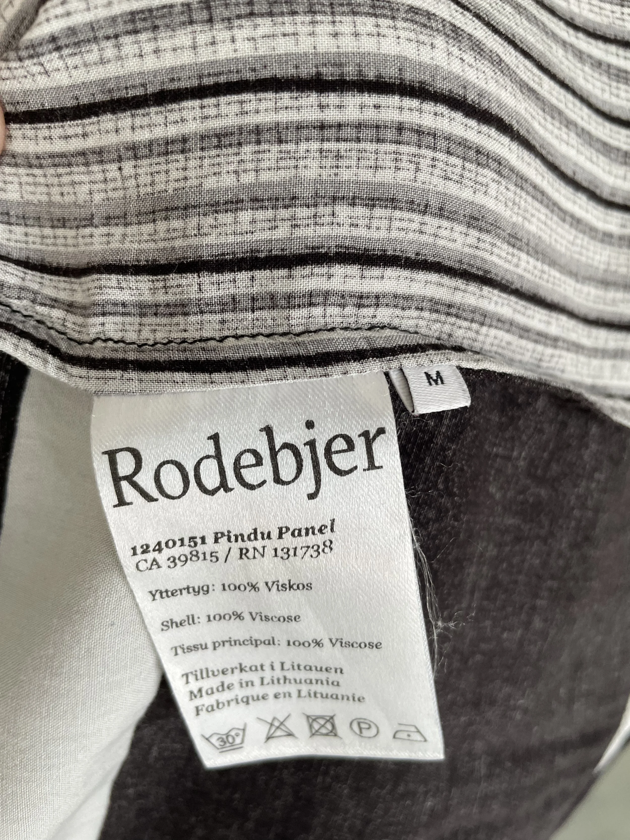 Close-up of the inner garment tag showing "Rodebjer," size "M," and care instructions for the 100% viscose material.