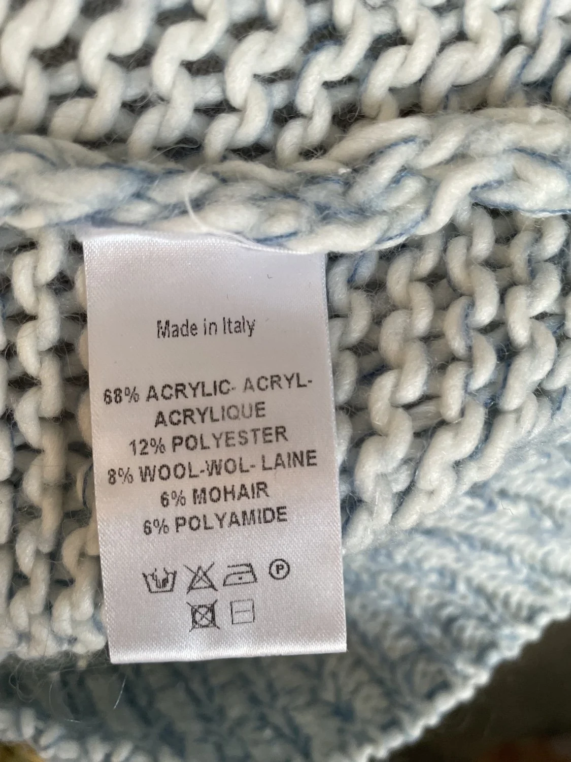 Close-up of the interior care label indicating the acrylic, wool, mohair blend and Made in Italy details.