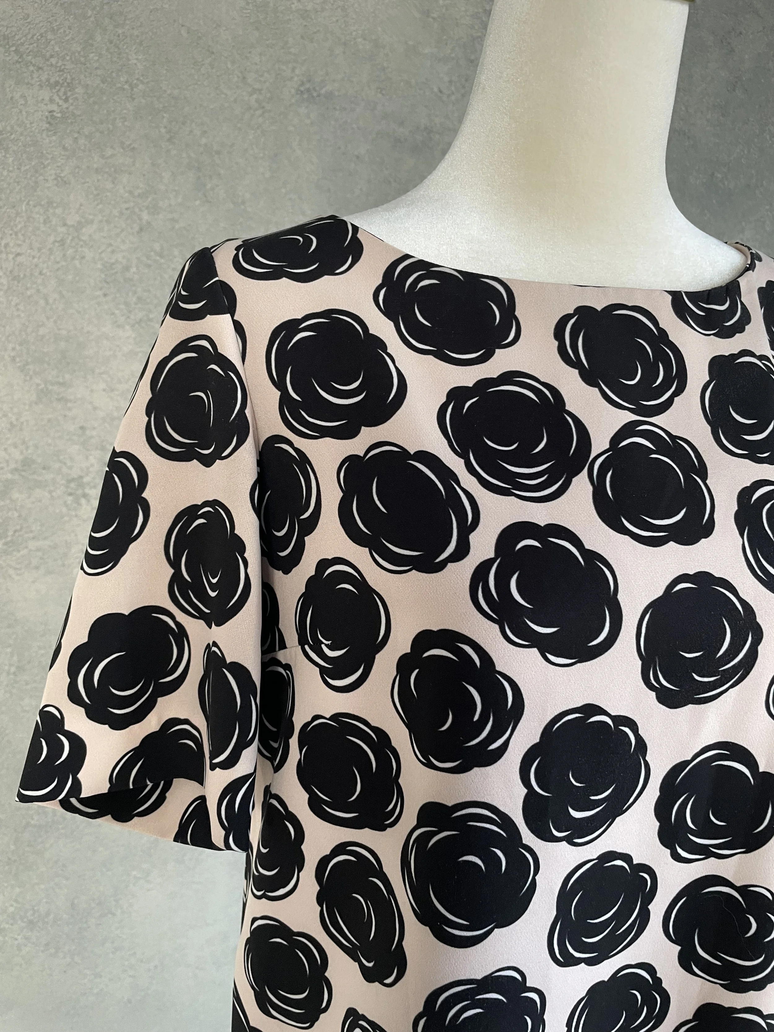 Close-up detail of the Gigue dress fabric, highlighting the graphic black floral print on a nude background and the quality of the textile