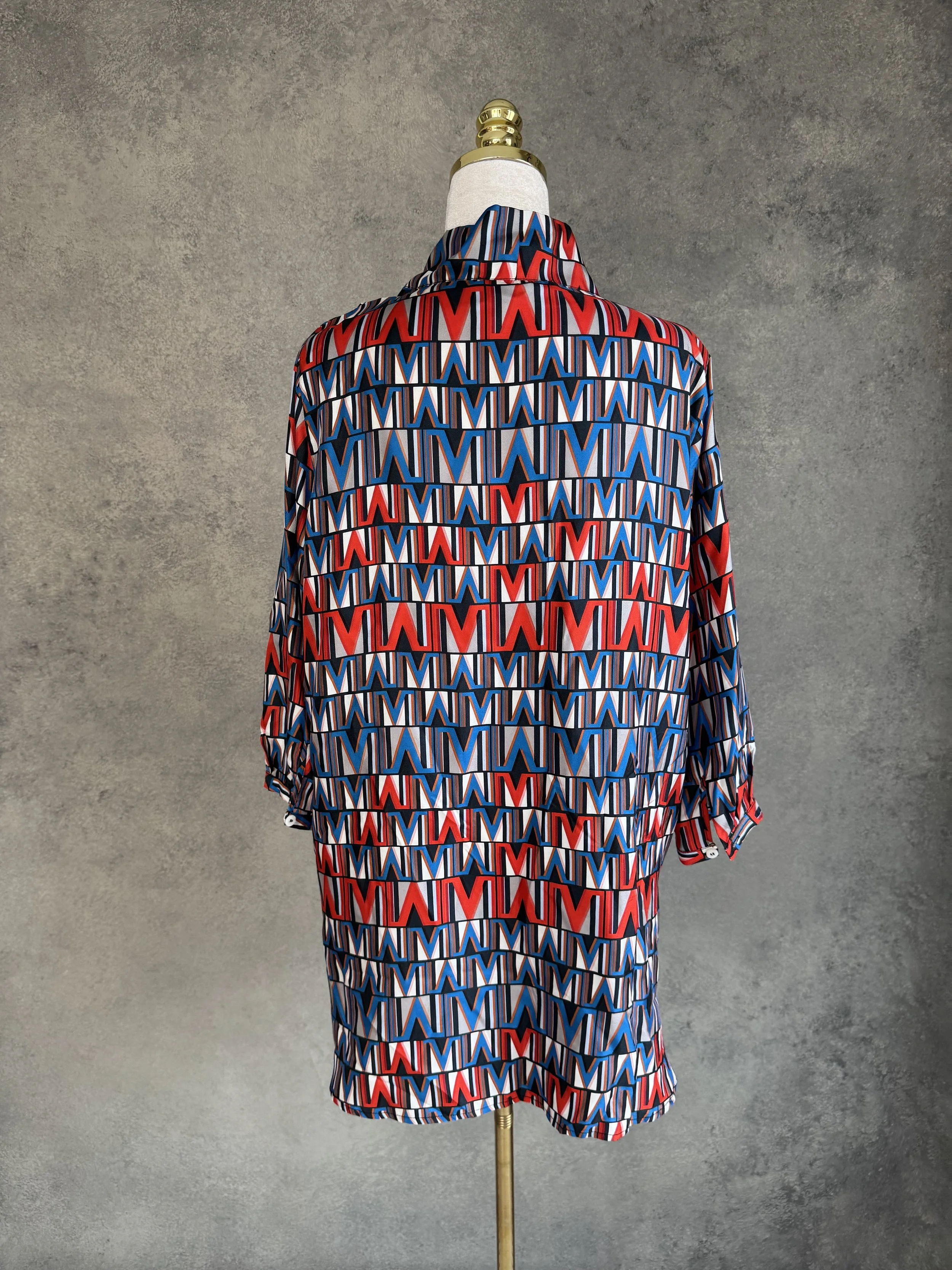 Rear view of the (THE MERCER) N.Y. geometric silk blouse on a mannequin.