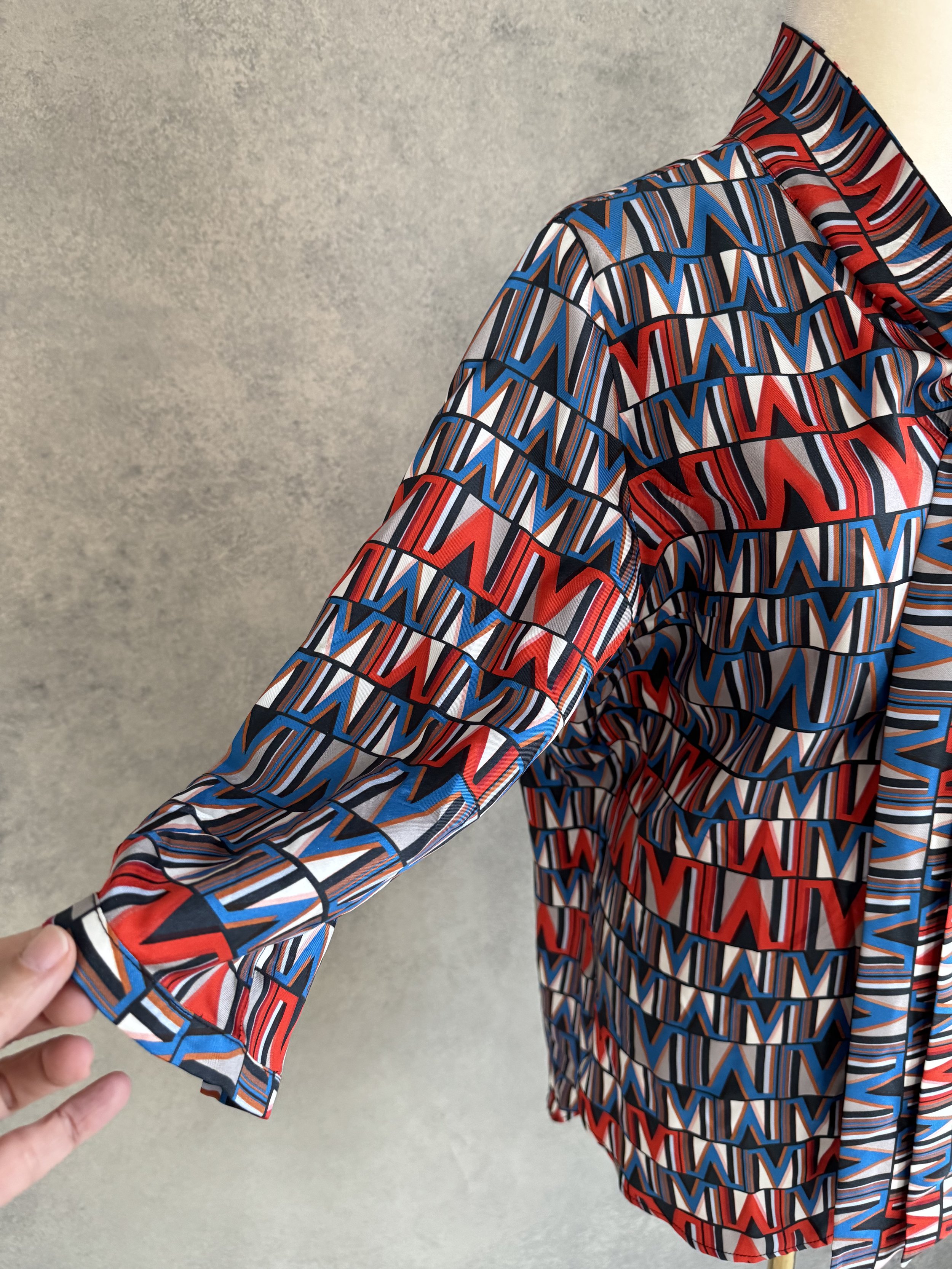 Close-up of the 100% silk fabric, highlighting the crimson red, electric blue, charcoal, and cream geometric pattern.