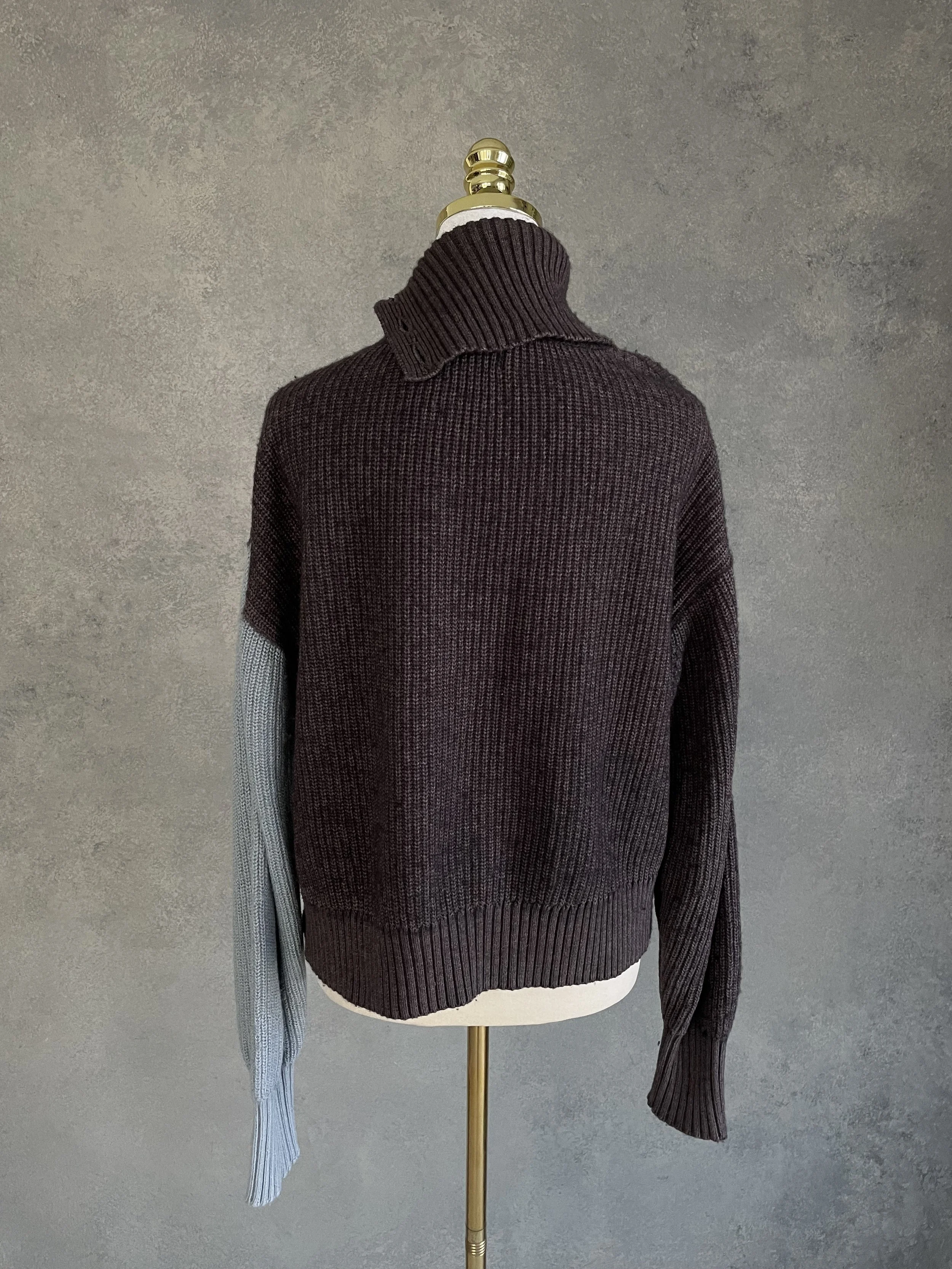 Back view of the Blanche sweater, highlighting the color-blocked grey sleeve against the dark brown body.