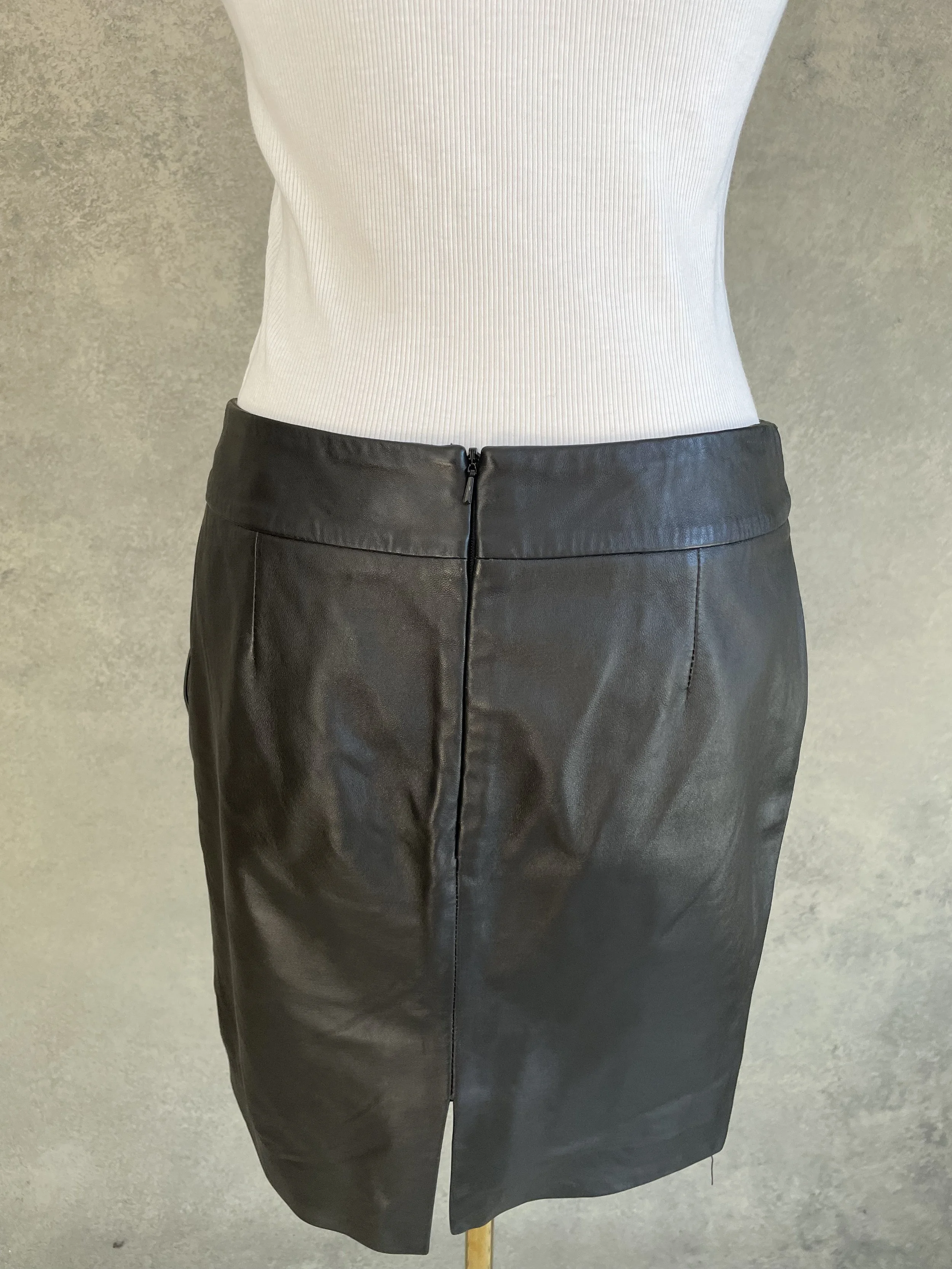 Close-up of the back zipper and seam detail on a black leather skirt.