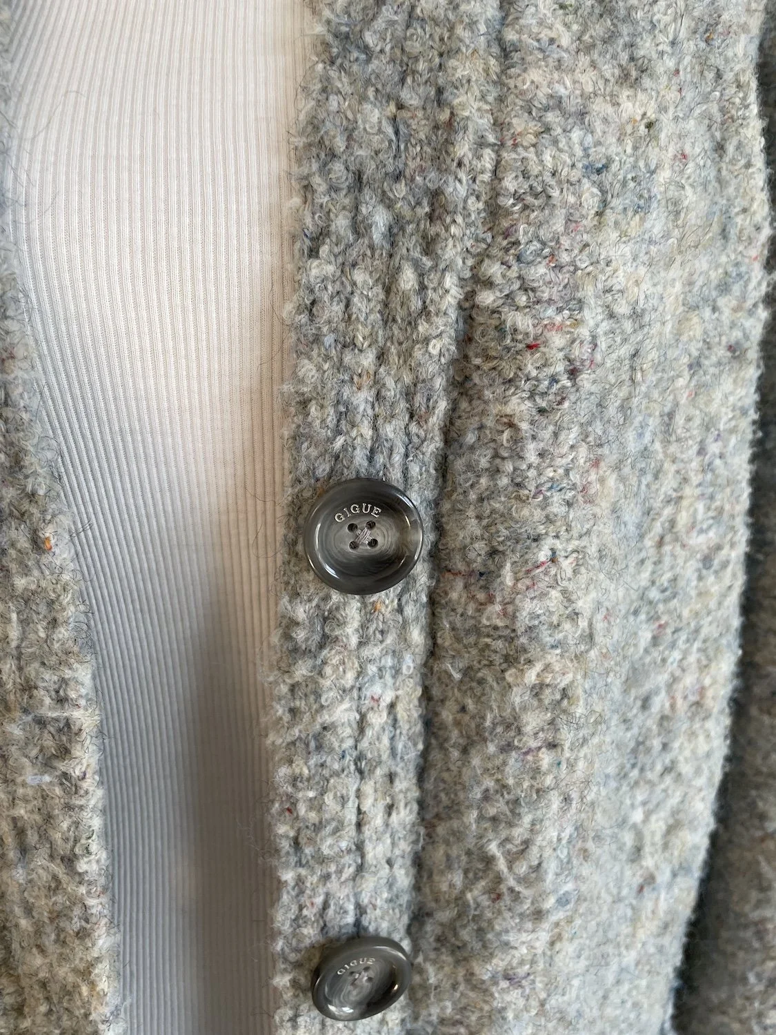 Close-up on the front button placket, highlighting the dark marbled buttons engraved with the Gigue logo.
