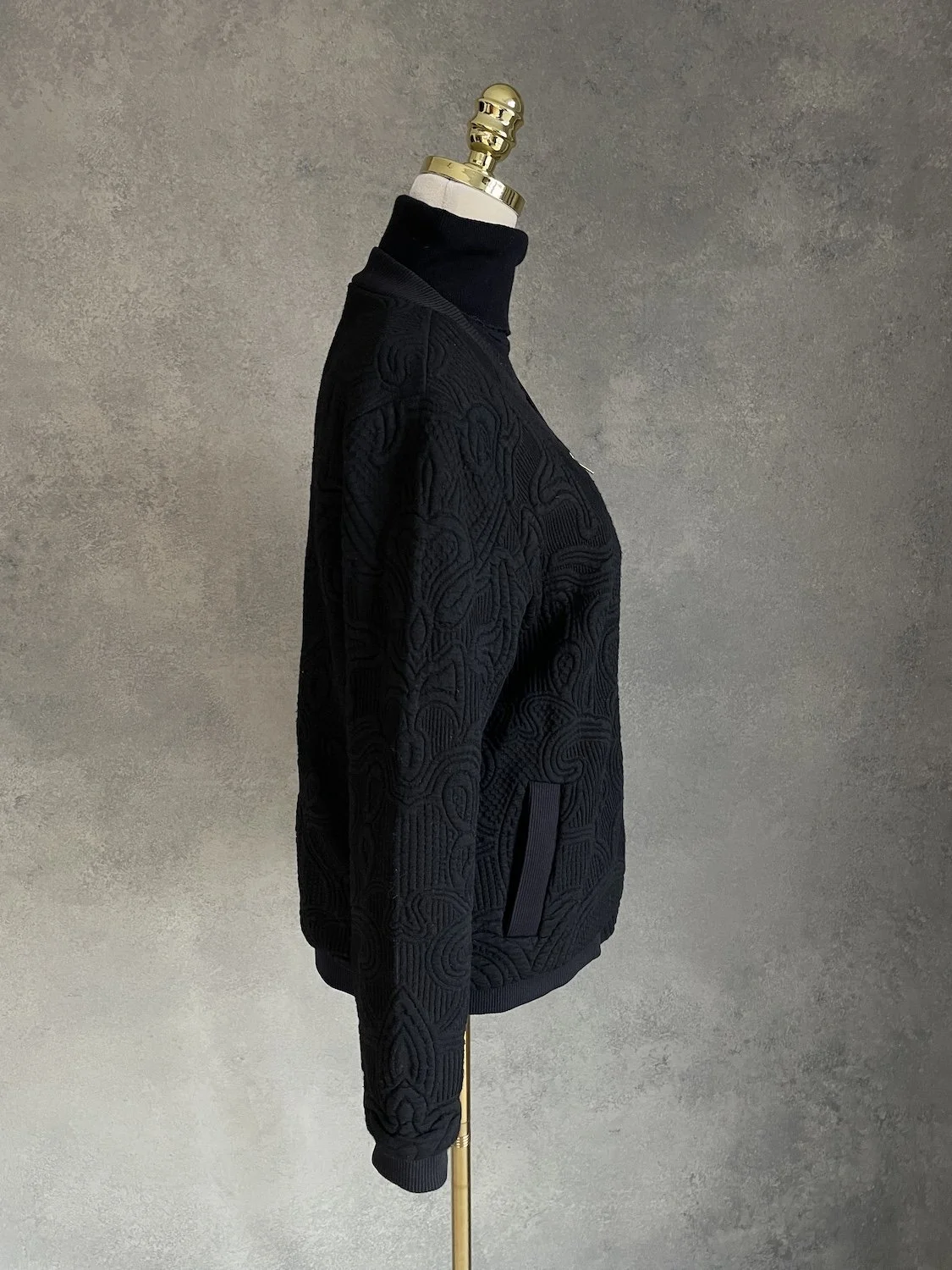 Side profile view showing sleeve taper, rib cuff, and structured torso volume.