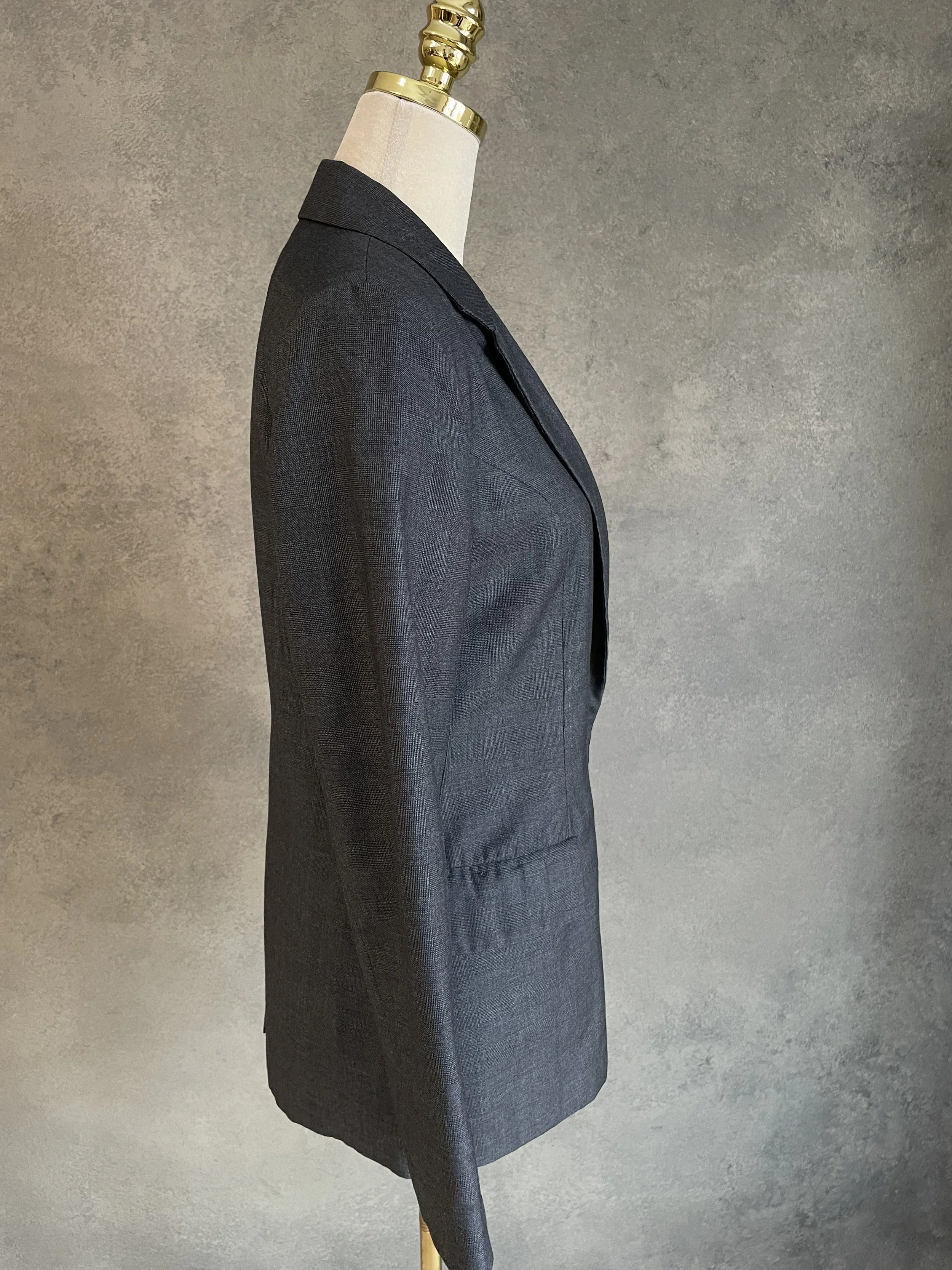 Side profile view of the MINIMUM blazer on a mannequin, displaying the clean lines of the sleeve and tailored silhouette.