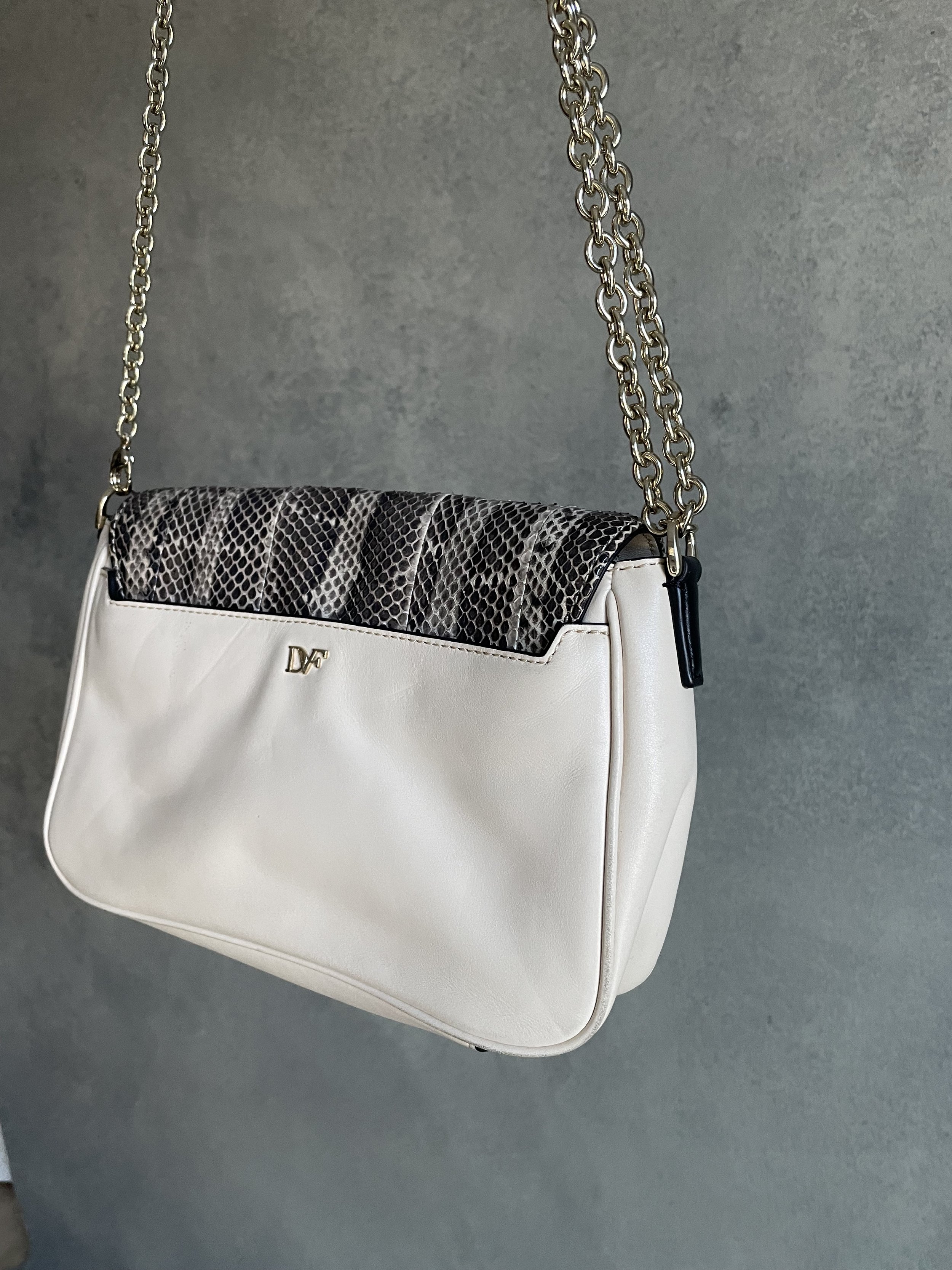 Detailed view of the gold-tone metal hardware and logo branding on the front of the DVF 440 envelope clutch.