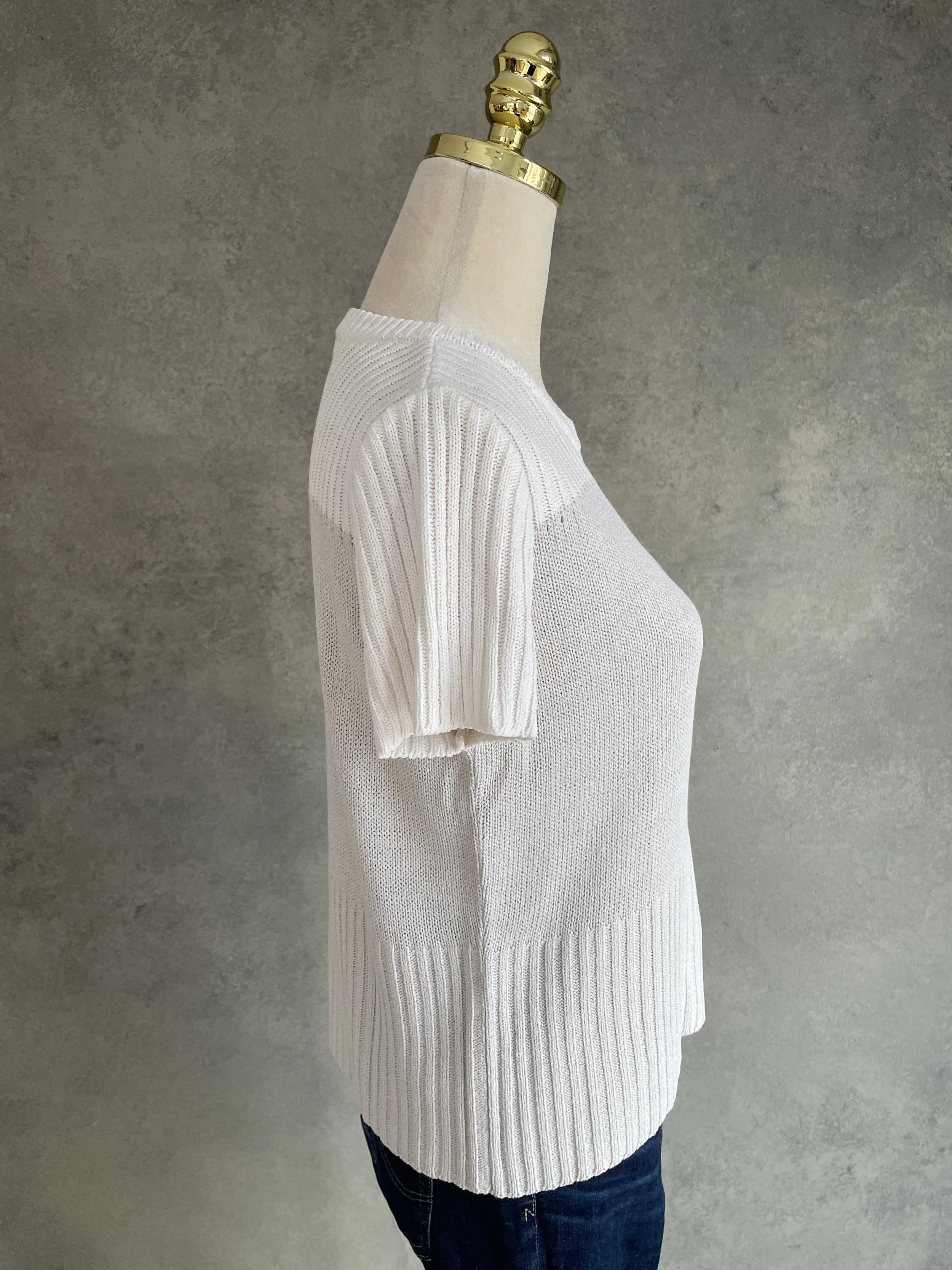 Side profile view of a beige Natan knit top on a mannequin, highlighting the ribbed sleeve texture.