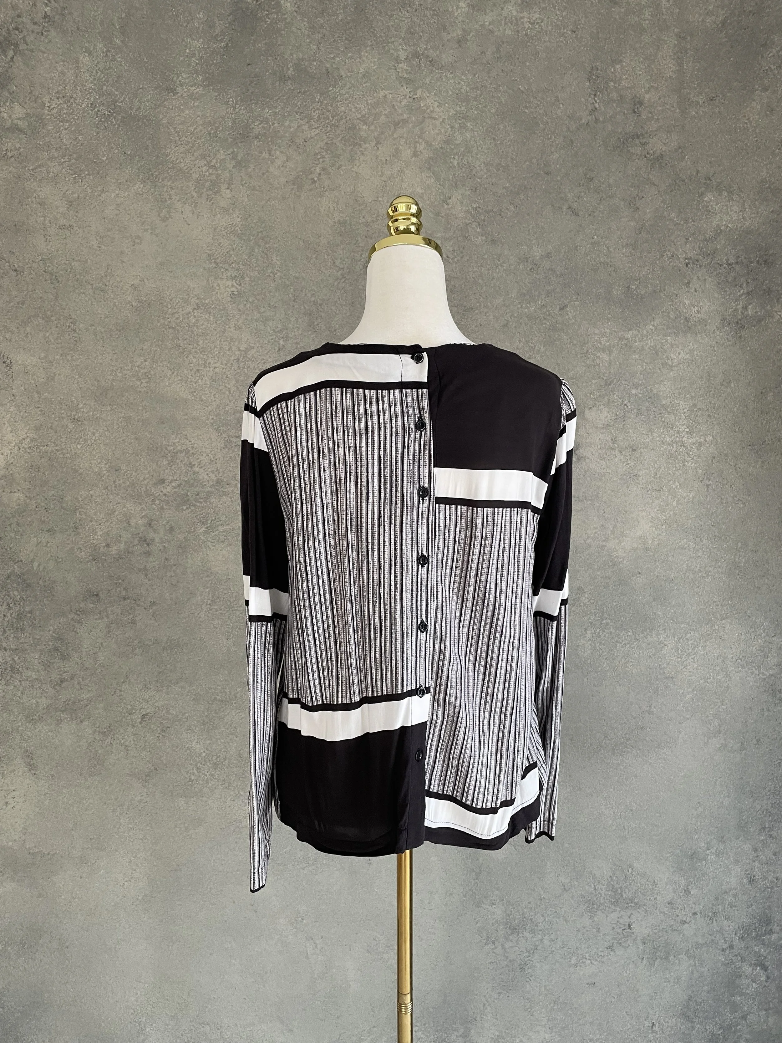 Back view of a Rodebjer long-sleeved blouse with a black and white graphic striped pattern and a vertical button placket.
