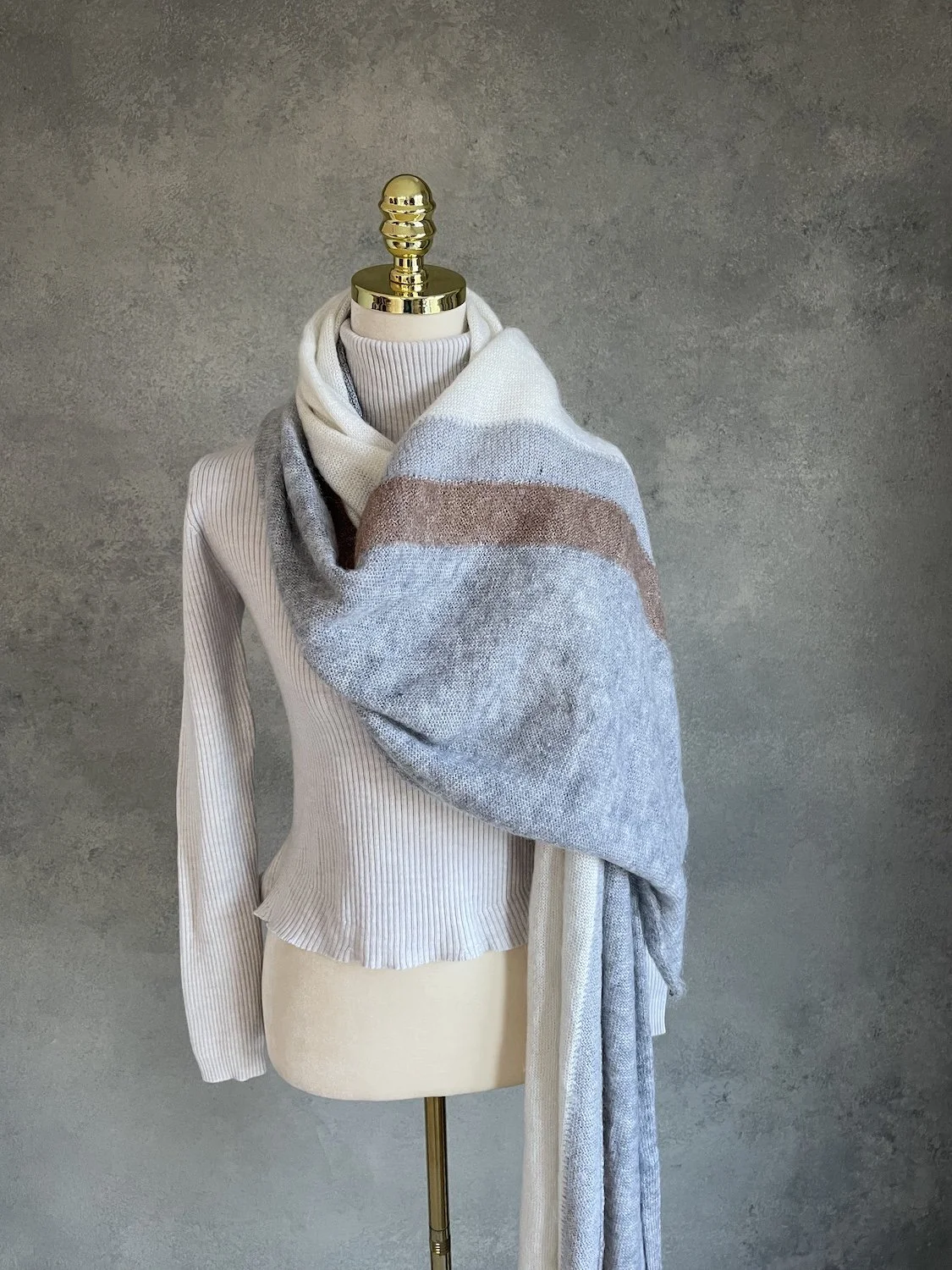 Scarf draped wide across the shoulder showcasing the horizontal bronze and grey colorblock stripe.