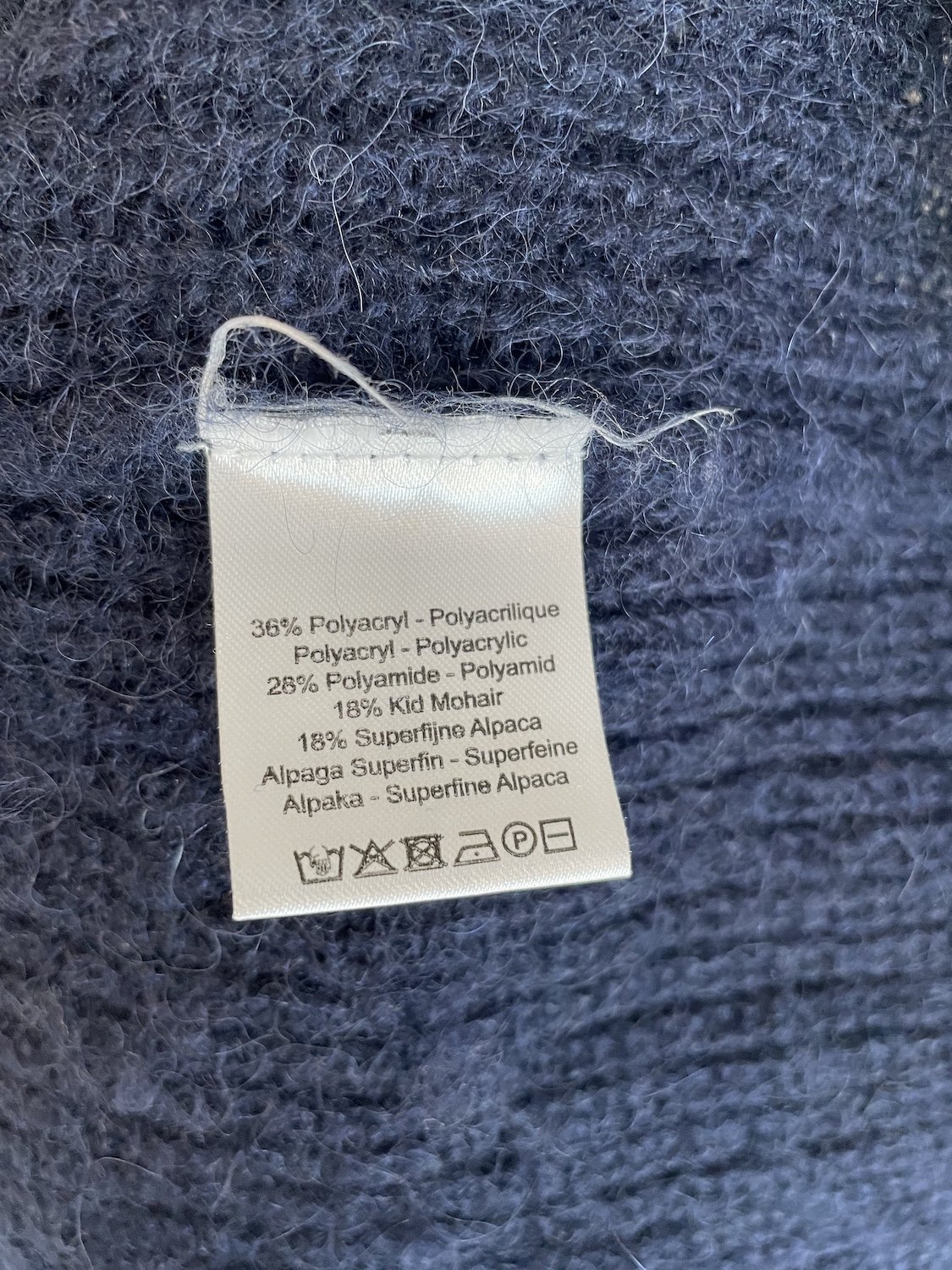 Close-up of the interior care label indicating the polyacrylic, polyamide, kid mohair, and superfine alpaca blend.