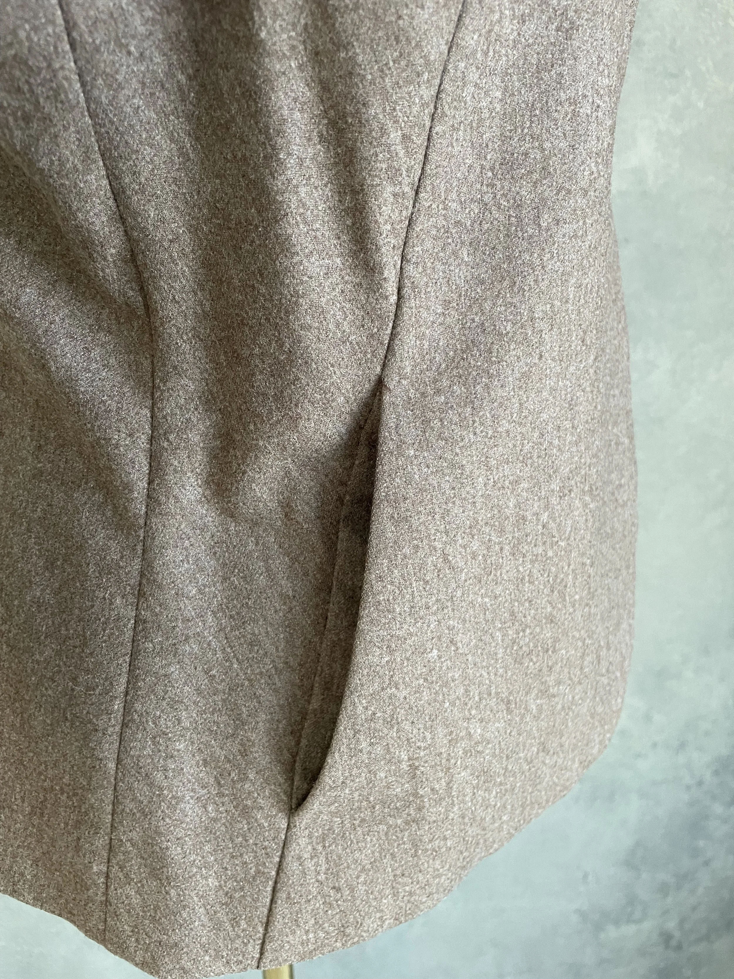 A focused close-up on the blazer's horizontal welt pocket located on the right front side of the jacket.