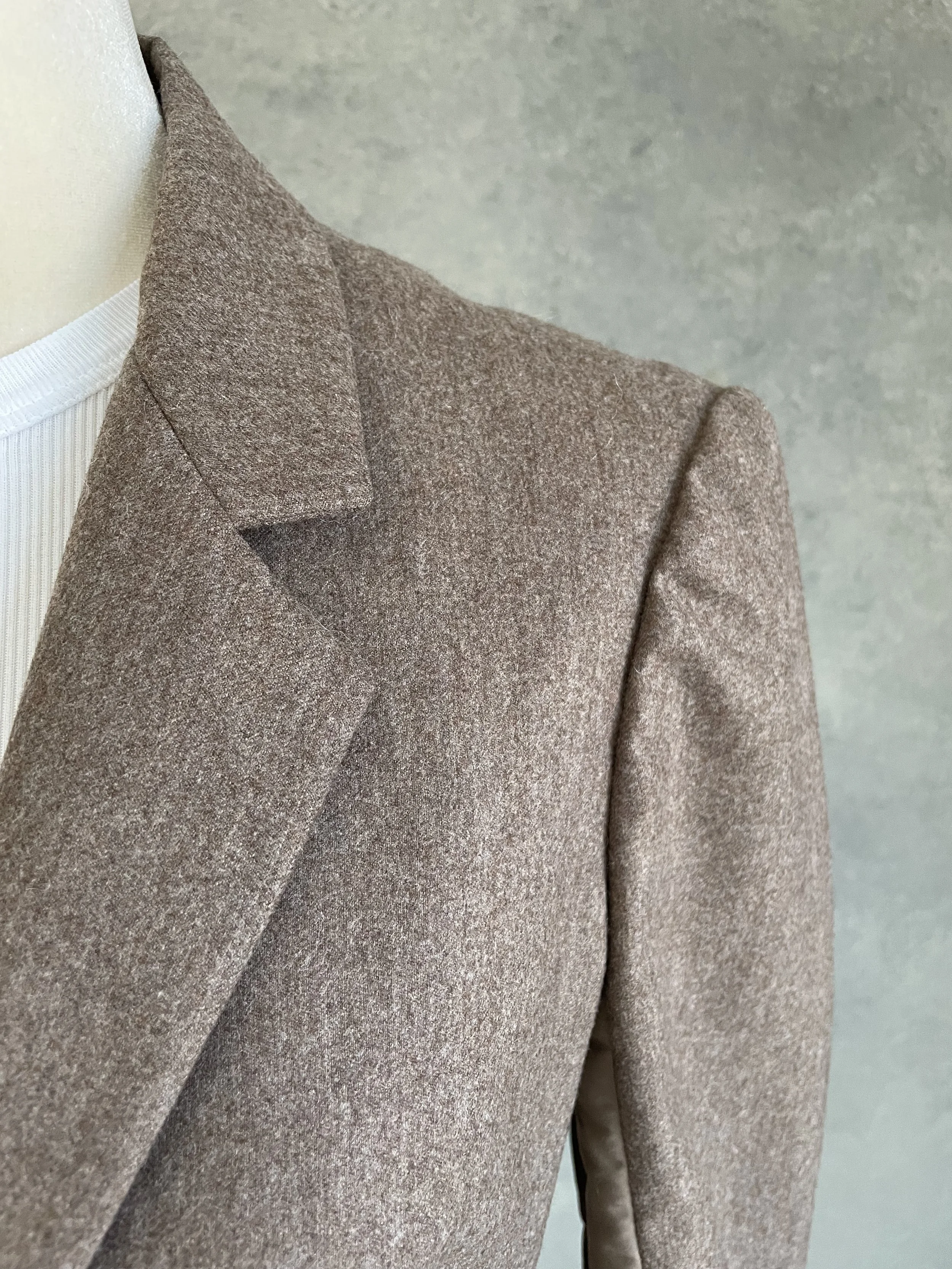 Another detail view of the collar and notch lapel from a slightly different angle, highlighting the precise stitching and the texture contrast with the smooth side panel.