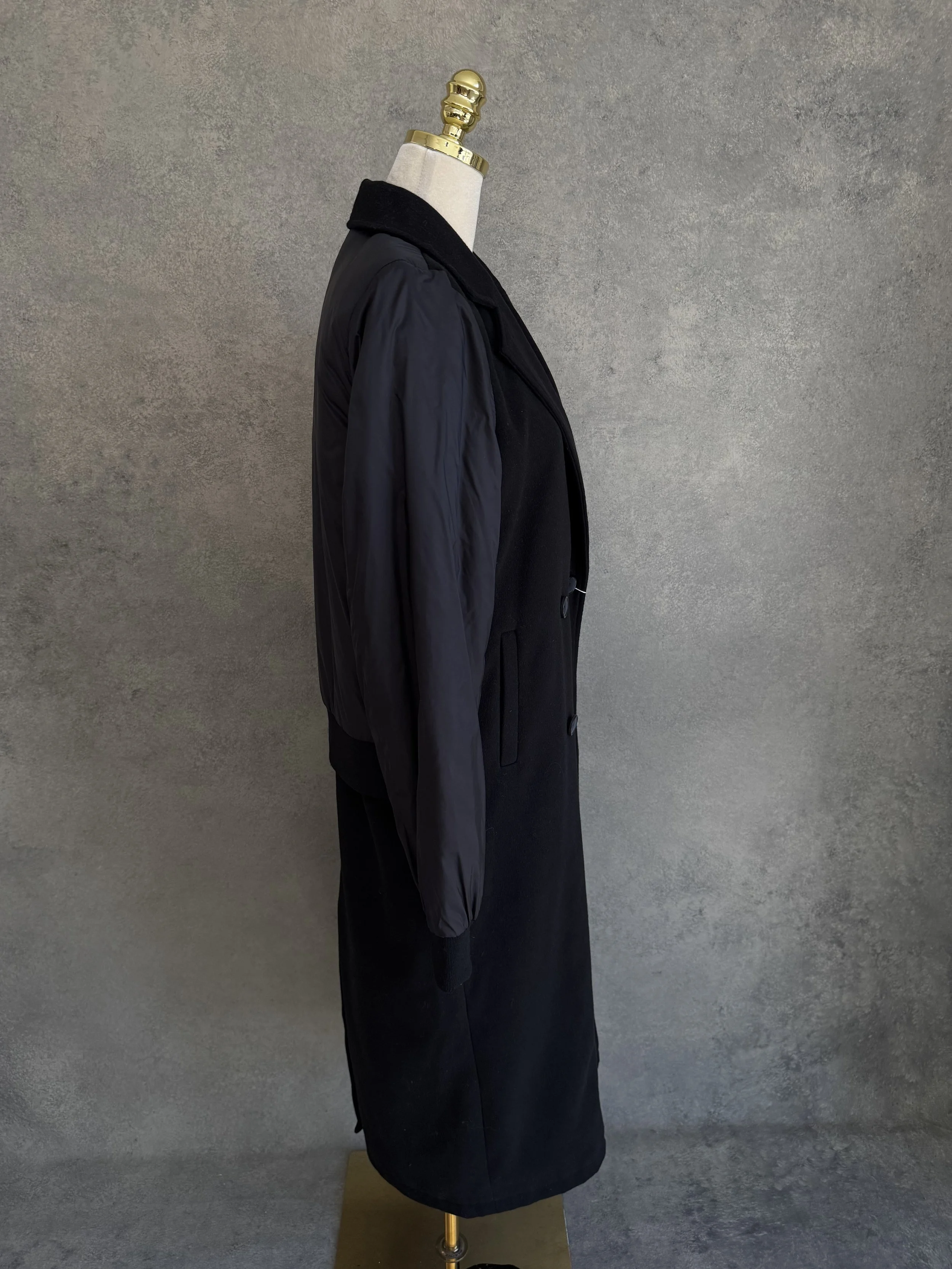 Side view of the long black anorak coat on the mannequin.