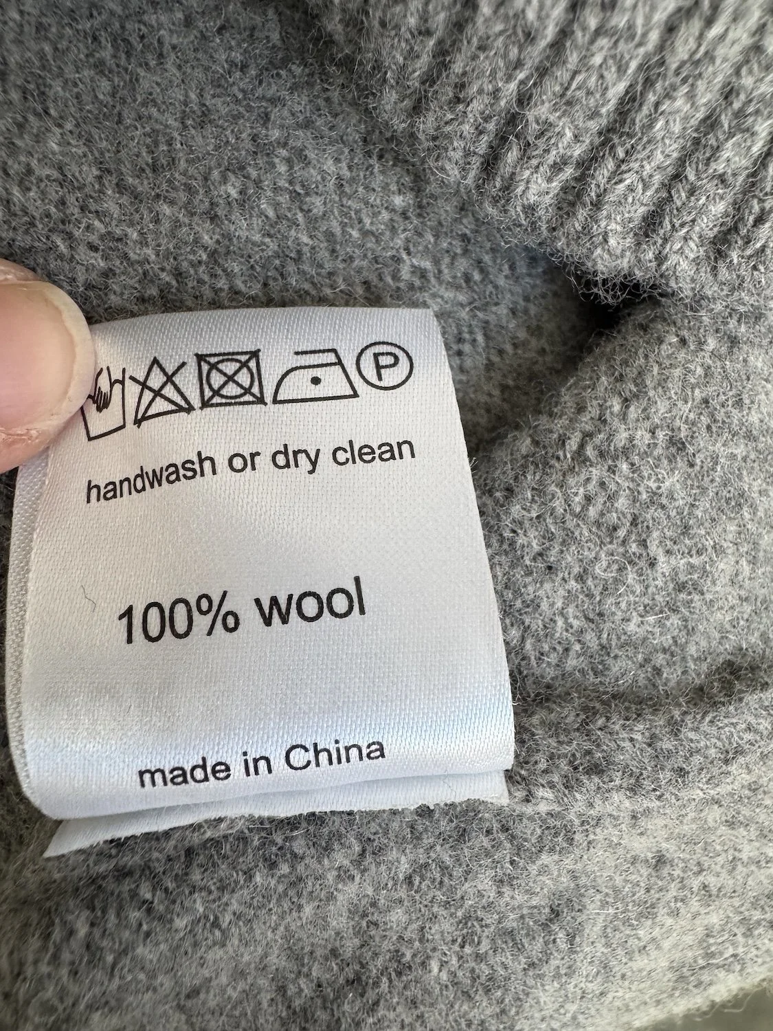 Close-up of the material tag indicating "100% wool" and hand wash care instructions.