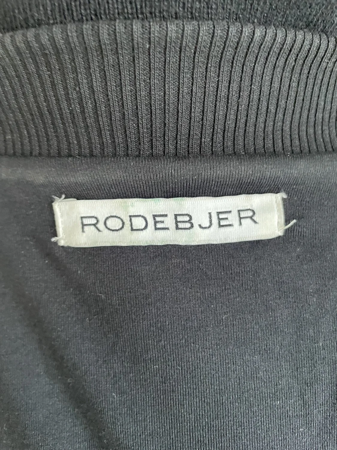 Close-up of the woven white 'RODEBJER' neck label.