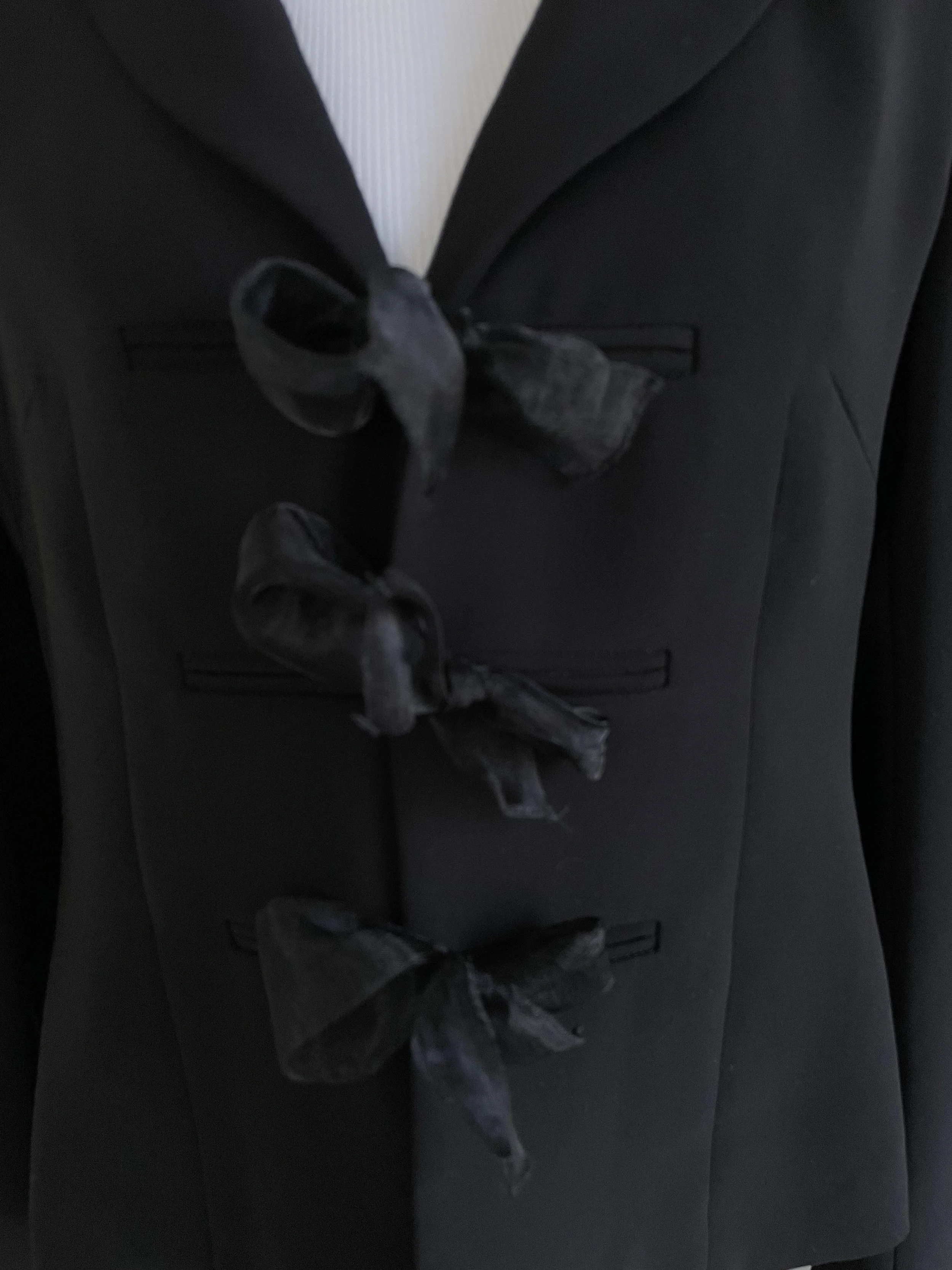 Detailed view of the three ribbon closures on the front of the blazer.