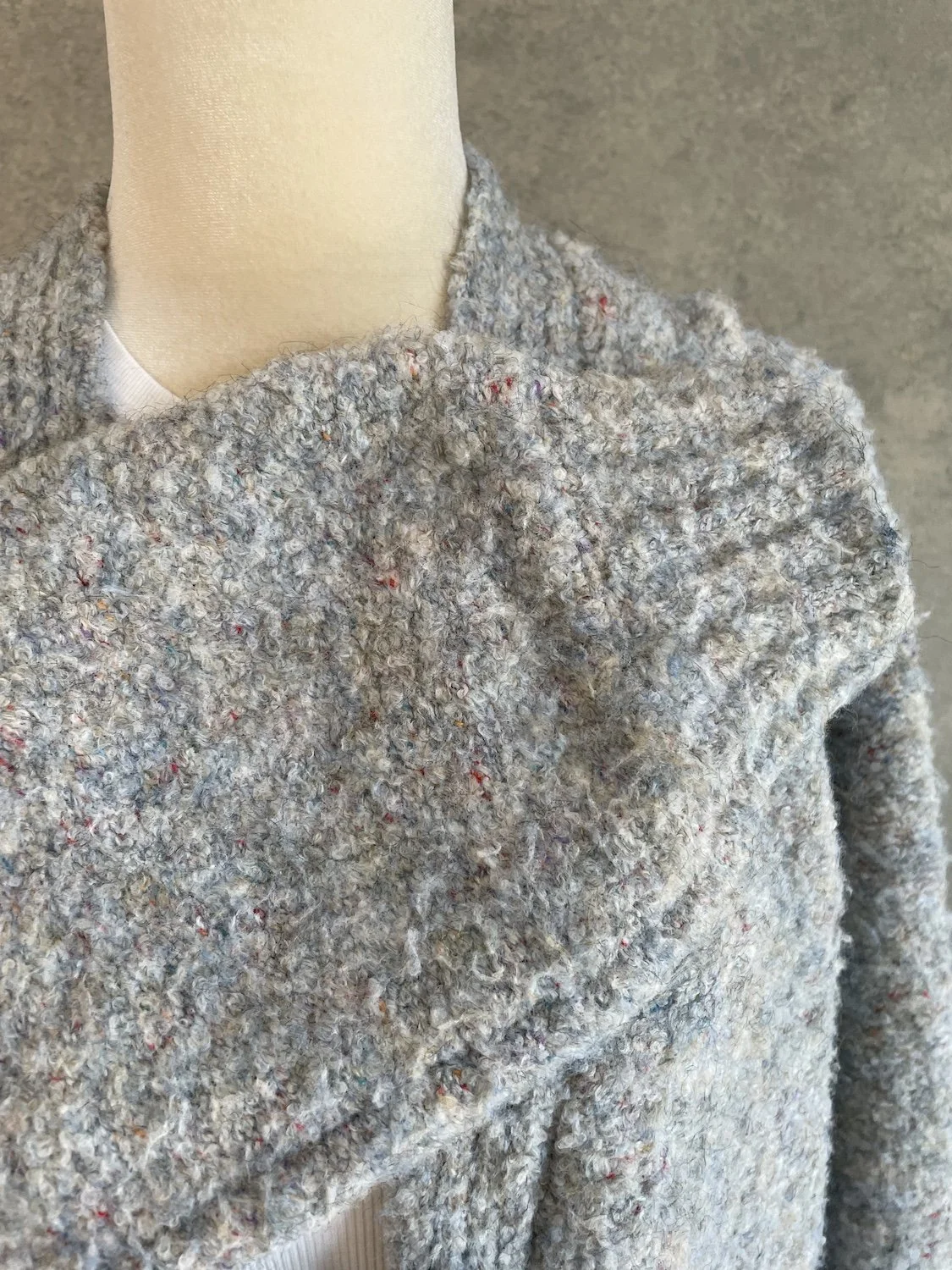 Close-up of the textured collar and shoulder area, displaying the multi-colored flecked bouclé knit.