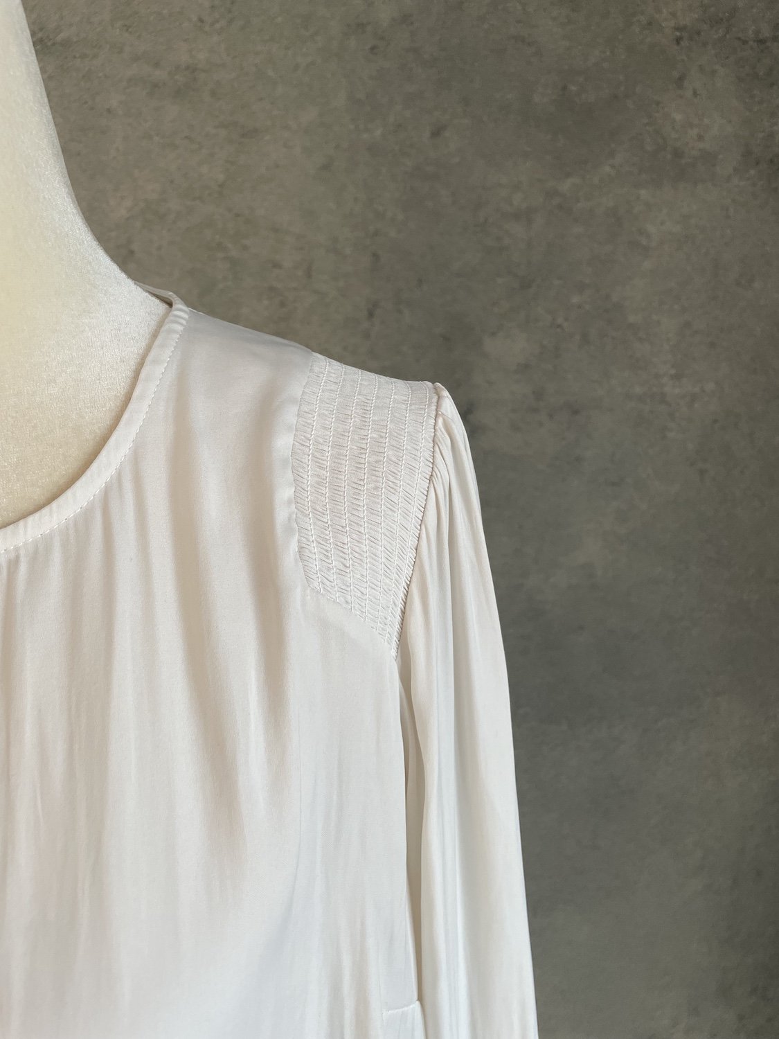 Close-up of the smocked shoulder yoke detail on the Gigue beige blouse, highlighting the fine texture and craftsmanship.