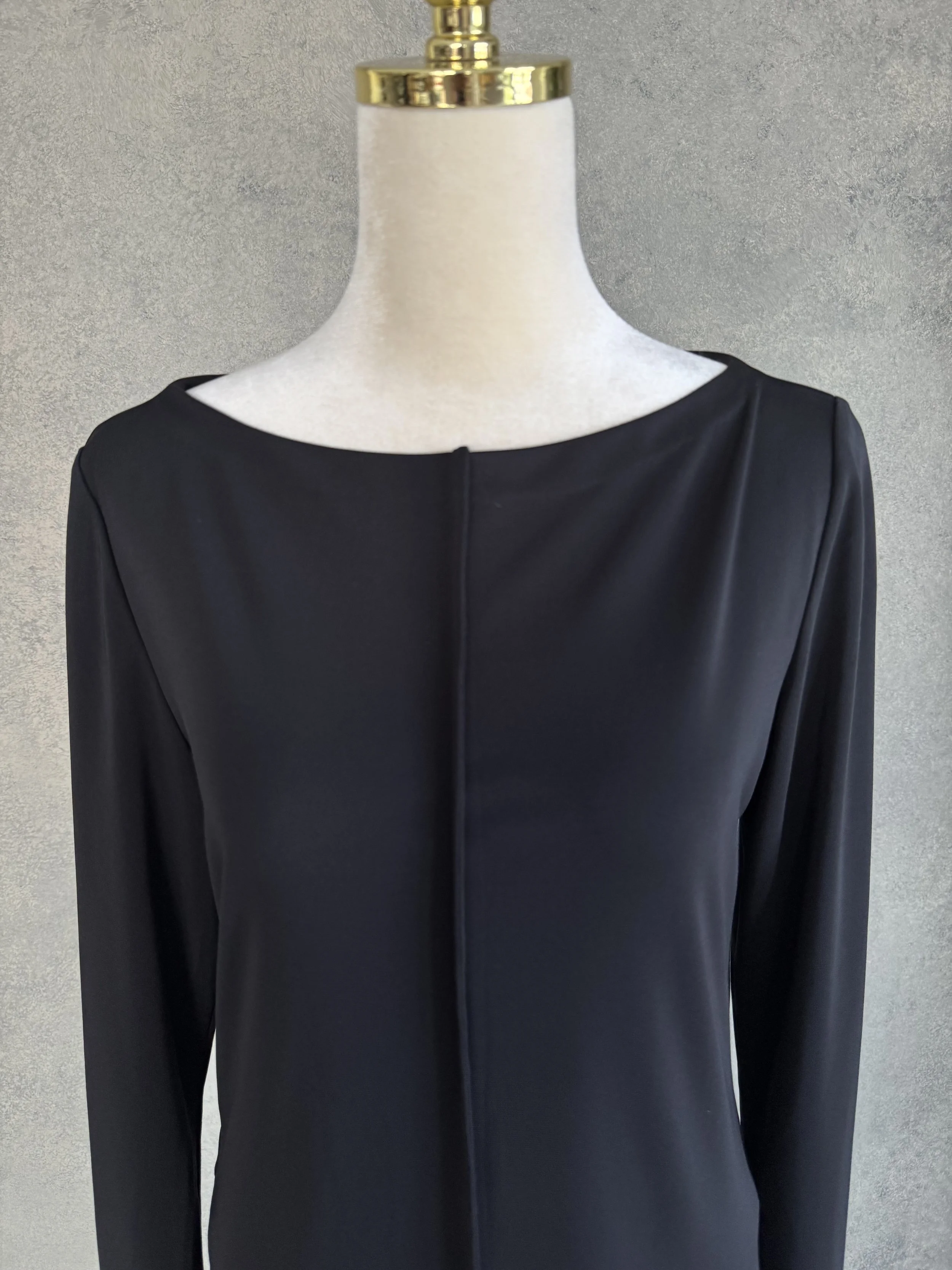 Close-up front view of the boat neckline and central vertical seam detailing on the black Filippa K dress.