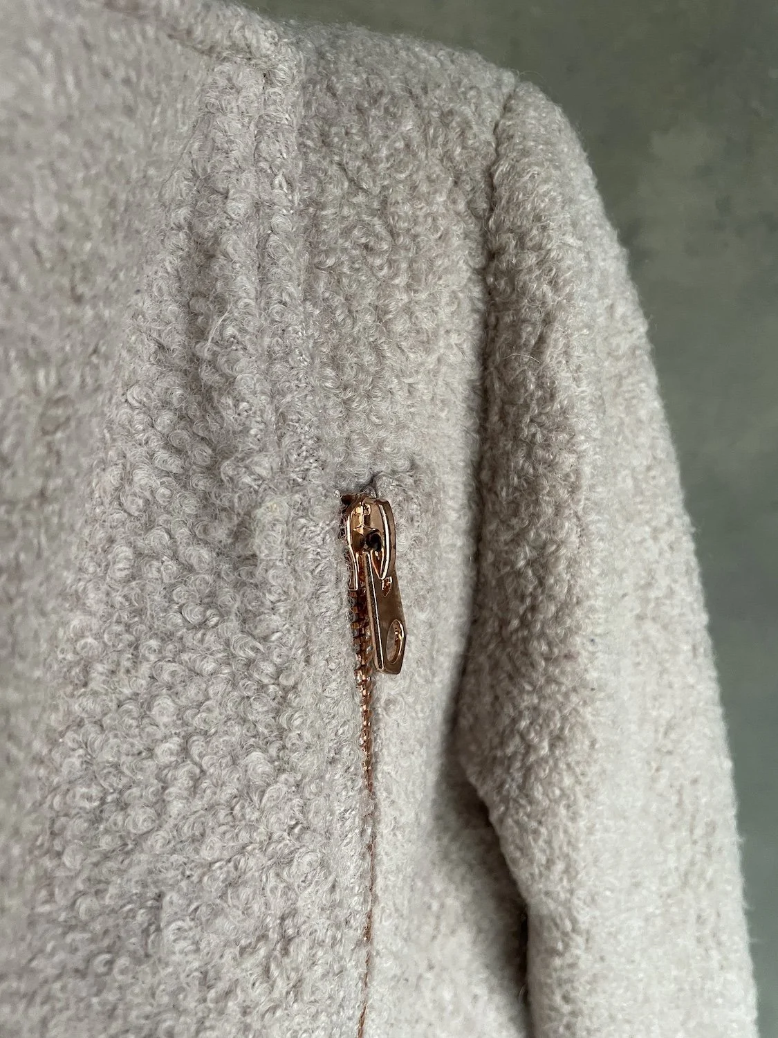 Close-up of the rose-gold zipper pull and textured loop fabric.