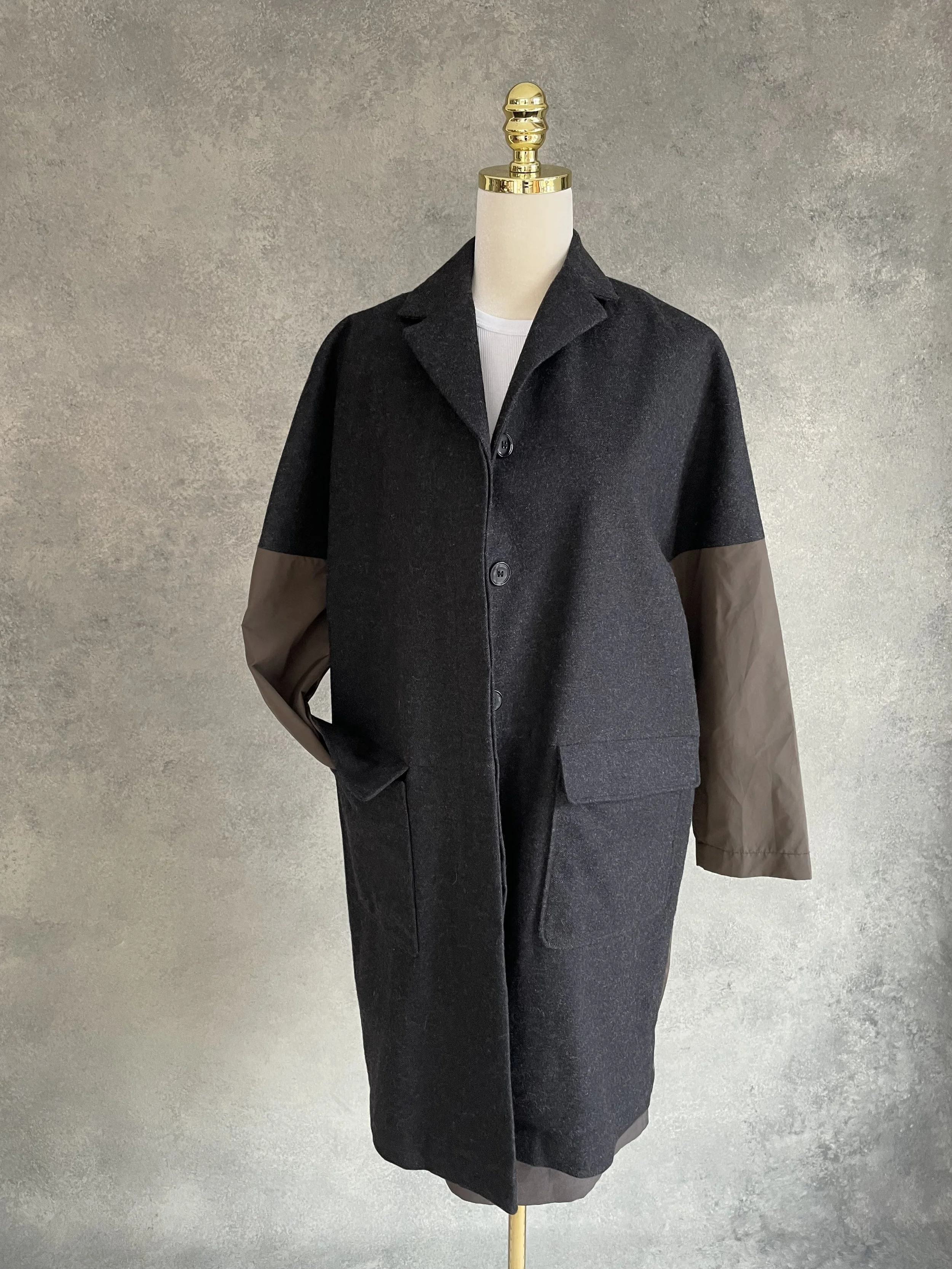 Front view of the Rue Blanche coat, showing the contrast between the dark wool and brown sleeve panels