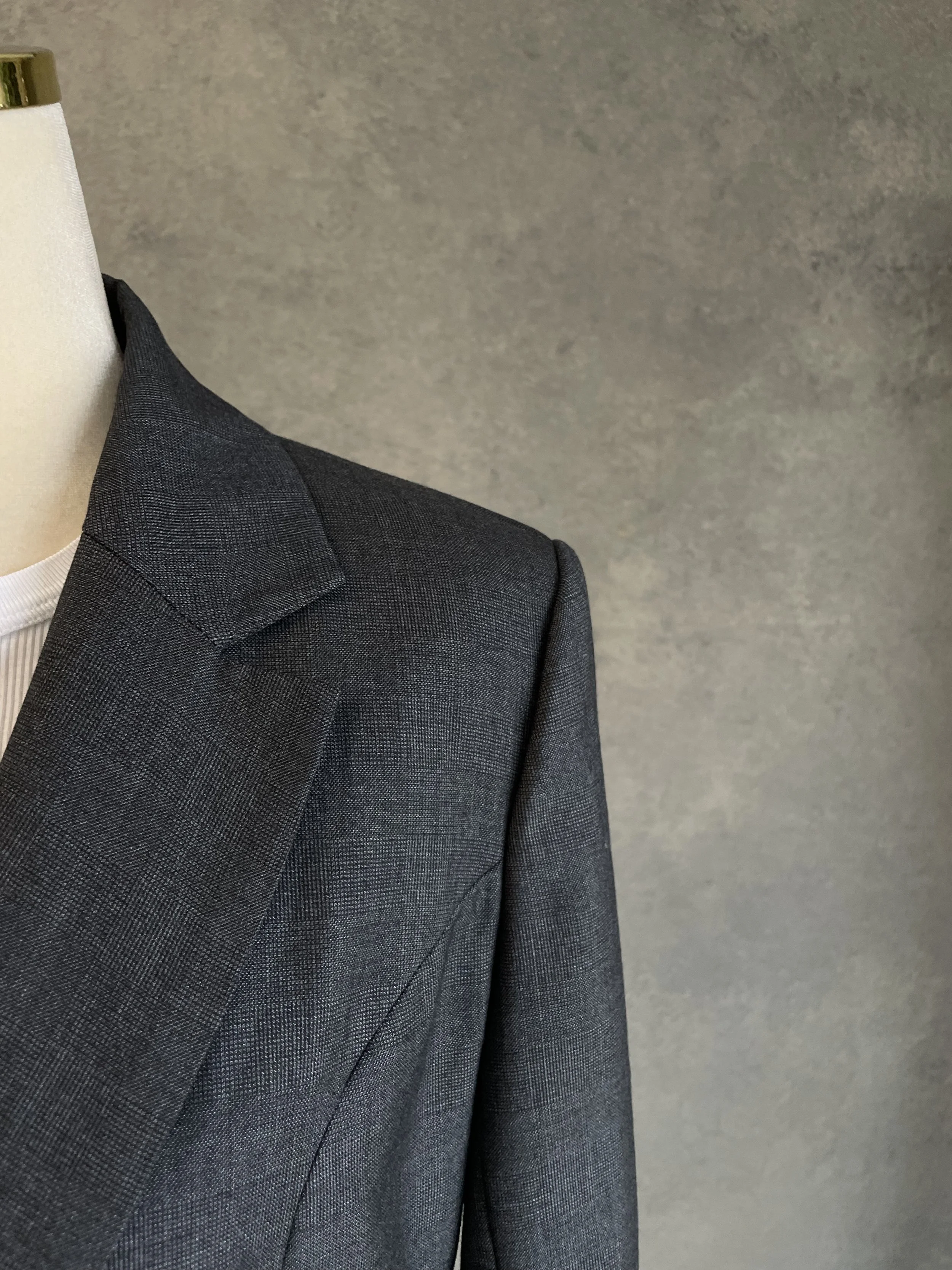 Close-up of the structured shoulder and collar line, highlighting the dark grey melange fabric texture.