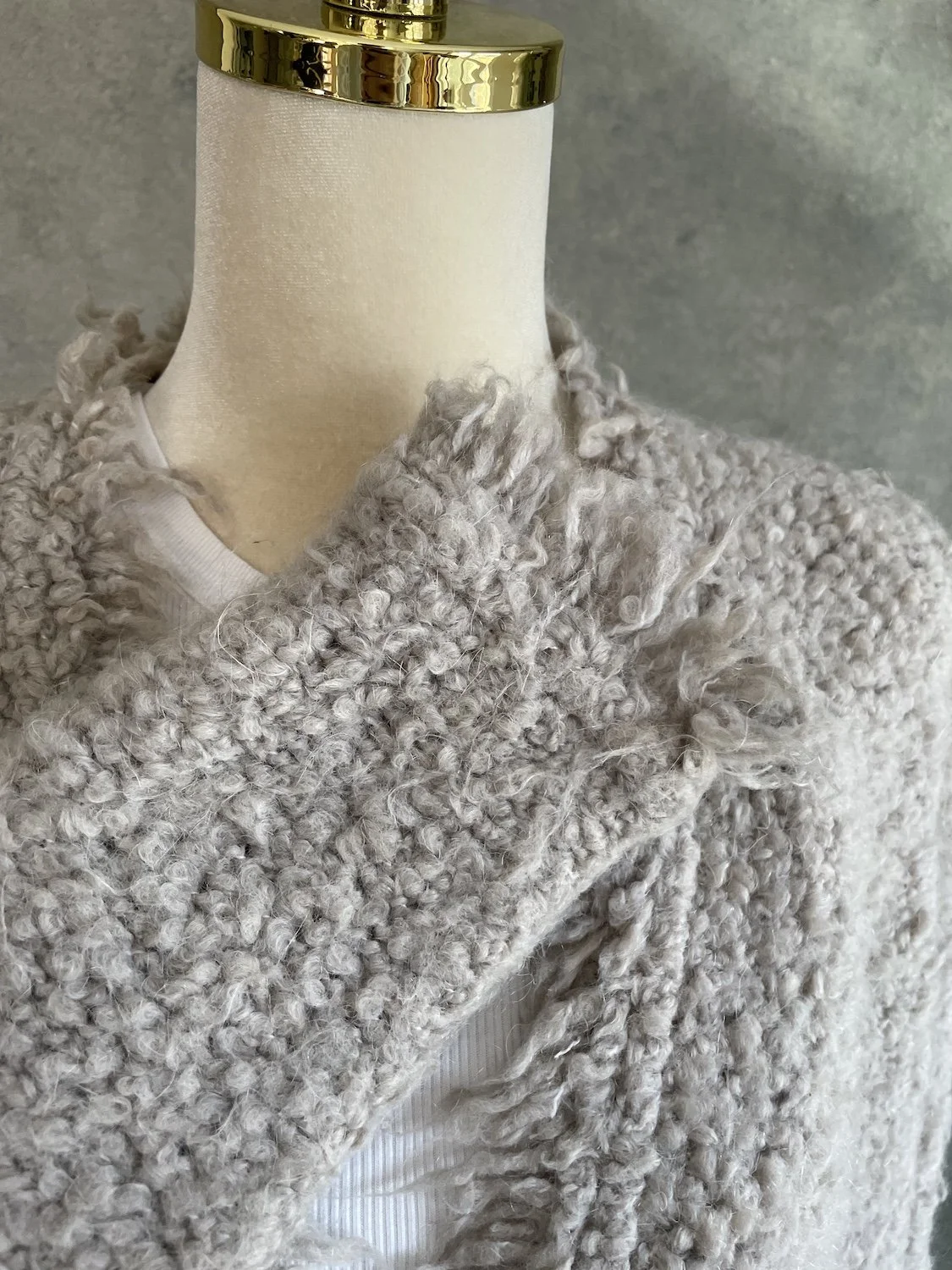 Detailed close-up of the frayed lapel edge and thick textured knit construction near the collar.